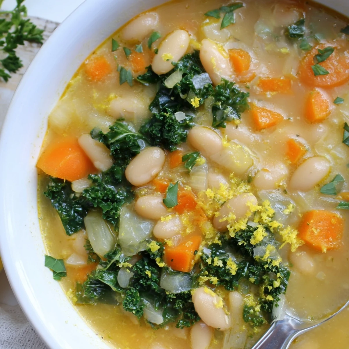 Hearty White Bean and Kale Soup with Lemon Zest, garnished with fresh parsley, served steaming in a rustic bowl.