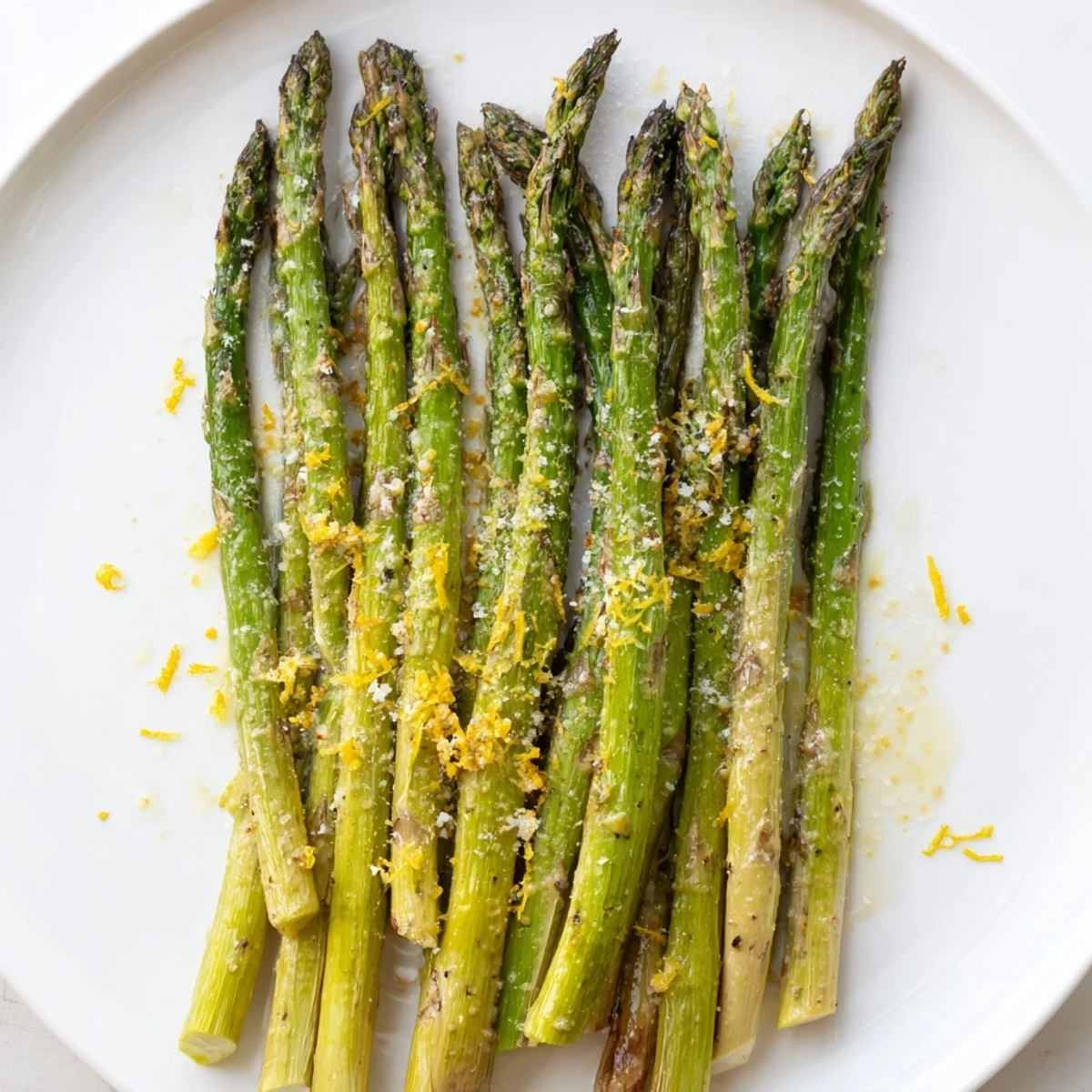 Golden roasted asparagus with Parmesan and lemon garnish, served hot as a bright Mediterranean side dish on a rustic plate.