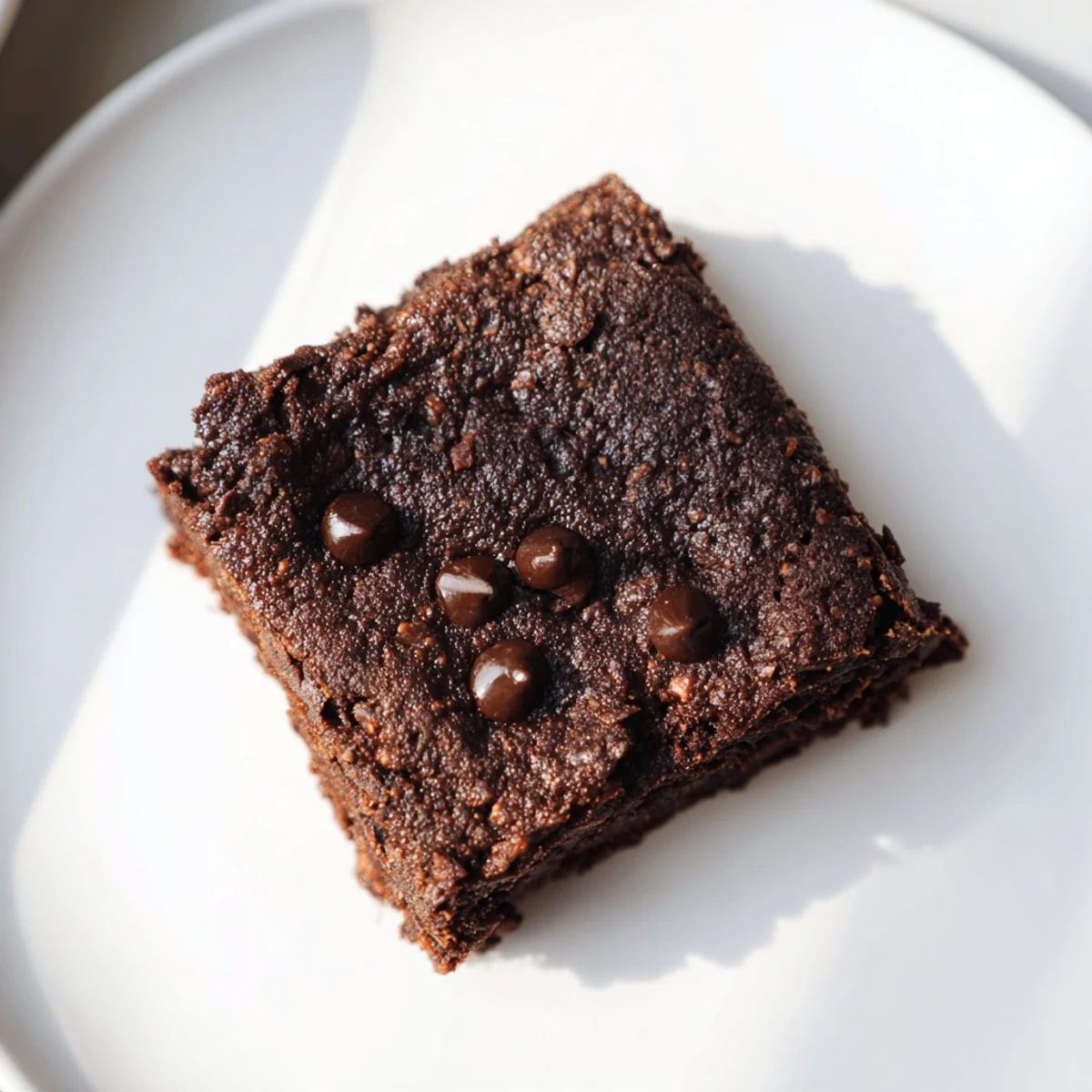 A close-up shows fudgy Gluten-Free Almond Flour Brownies with gooey chocolate chunks, served on a white plate.  