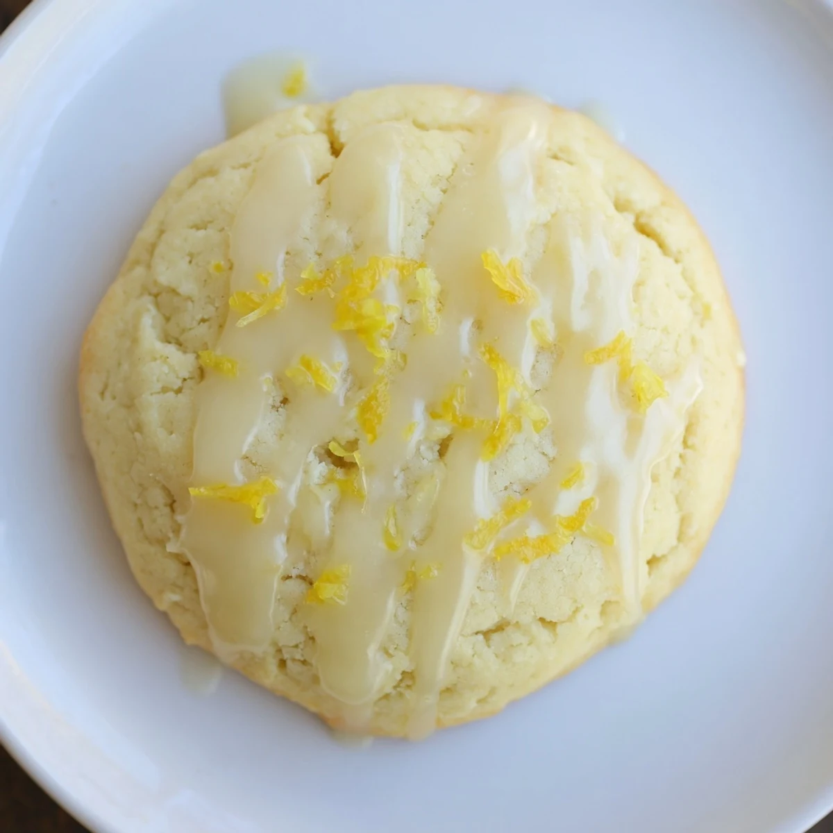 Close-up of Lemon Ricotta Cookies showing soft, pillowy texture and glossy lemon glaze on a marble counter.