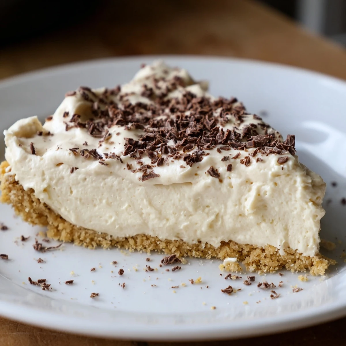 Freshly sliced Irish Cream Cheesecake reveals a creamy filling on a buttery graham cracker crust, topped with chocolate shavings.