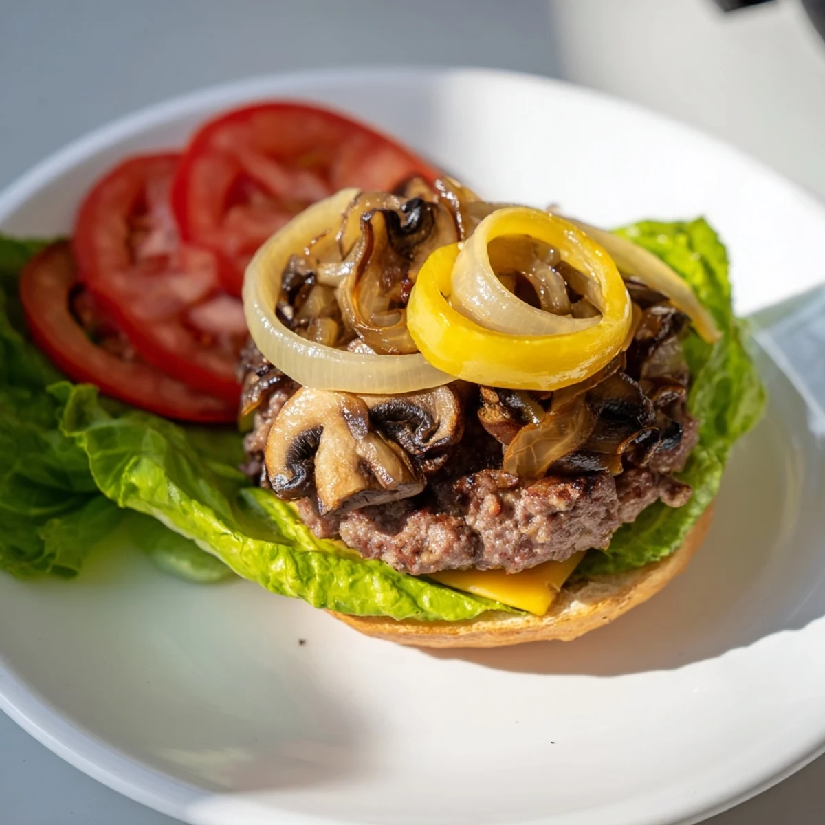 Close-up of a delicious Beef Burger with Caramelized Onions and Mushrooms on a plate, ready to be enjoyed.