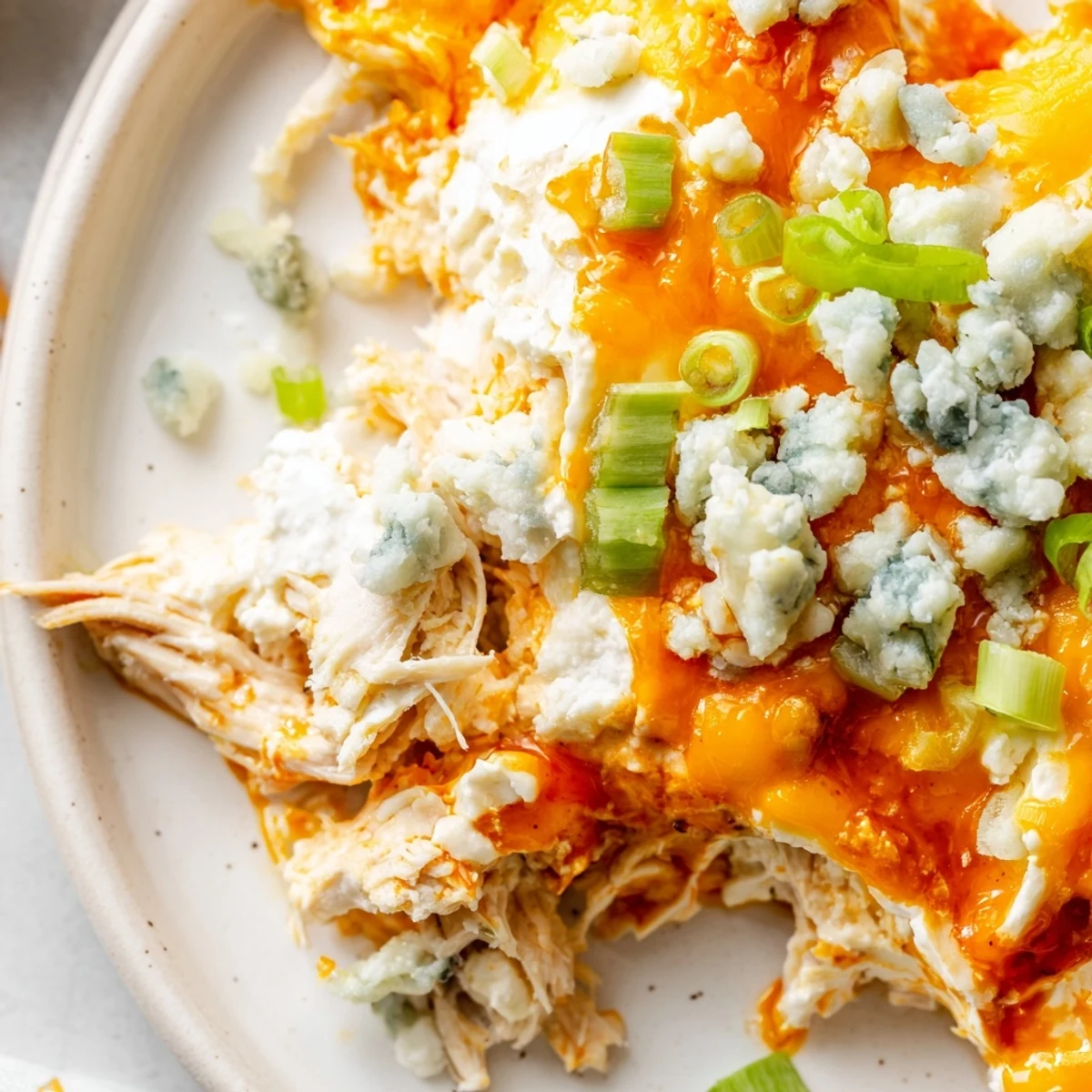 Creamy Keto Buffalo Chicken Dip in a warm baking dish, garnished with green onions and served with celery sticks.  
