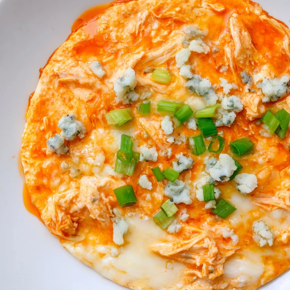 Hot Keto Buffalo Chicken Dip with melted mozzarella, cheddar, and blue cheese crumbles on top.  