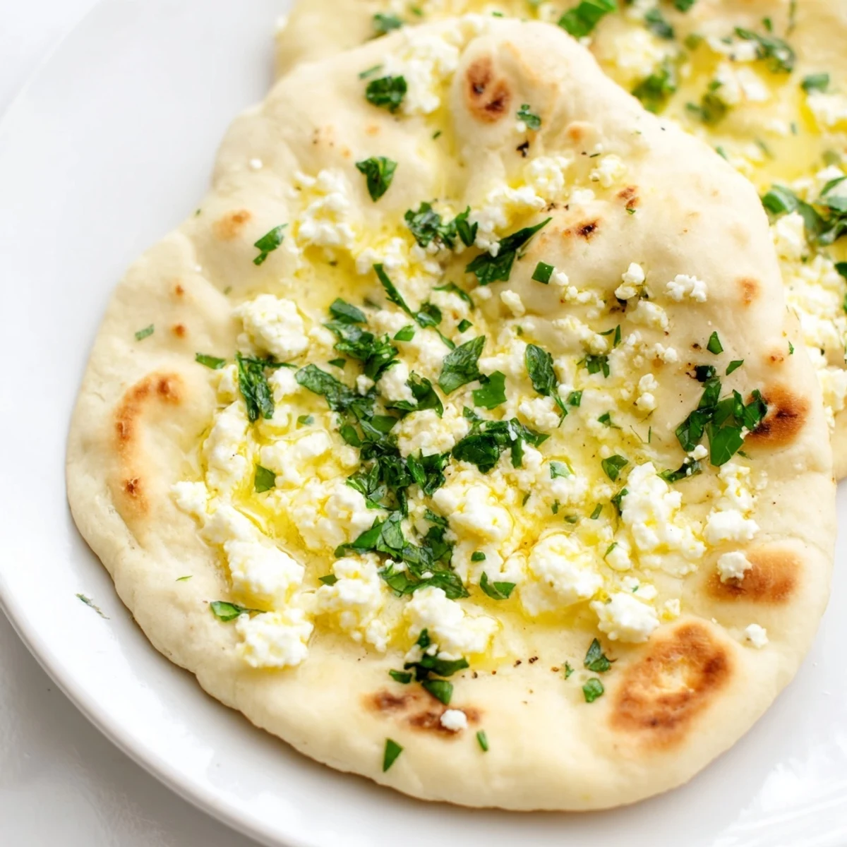 Soft Cottage Cheese Garlic Naan stacked and ready to serve, with a small dish of cilantro and garlic butter.