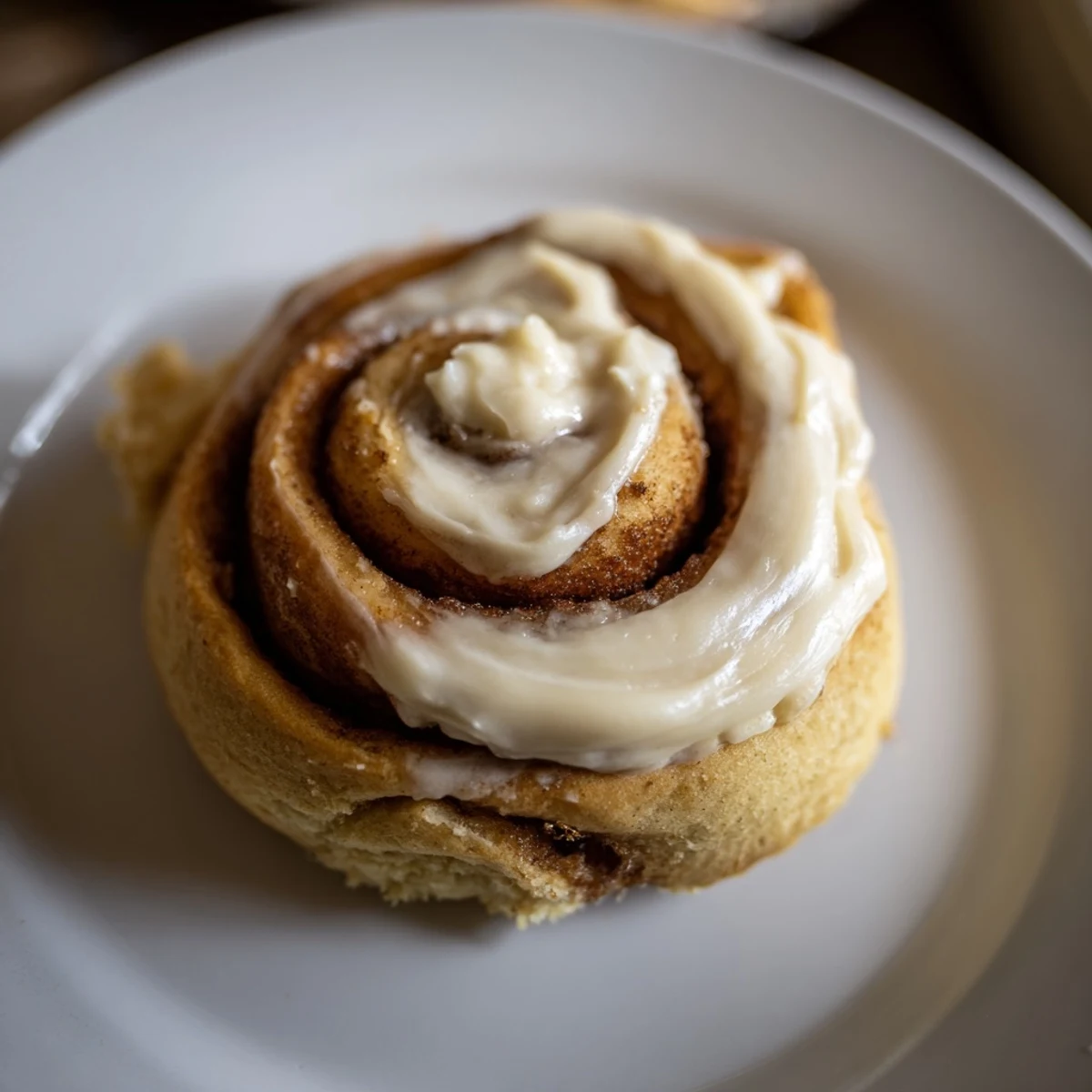 Golden brown Keto Cinnamon Buns with cream cheese icing on a white plate for a low carb breakfast.