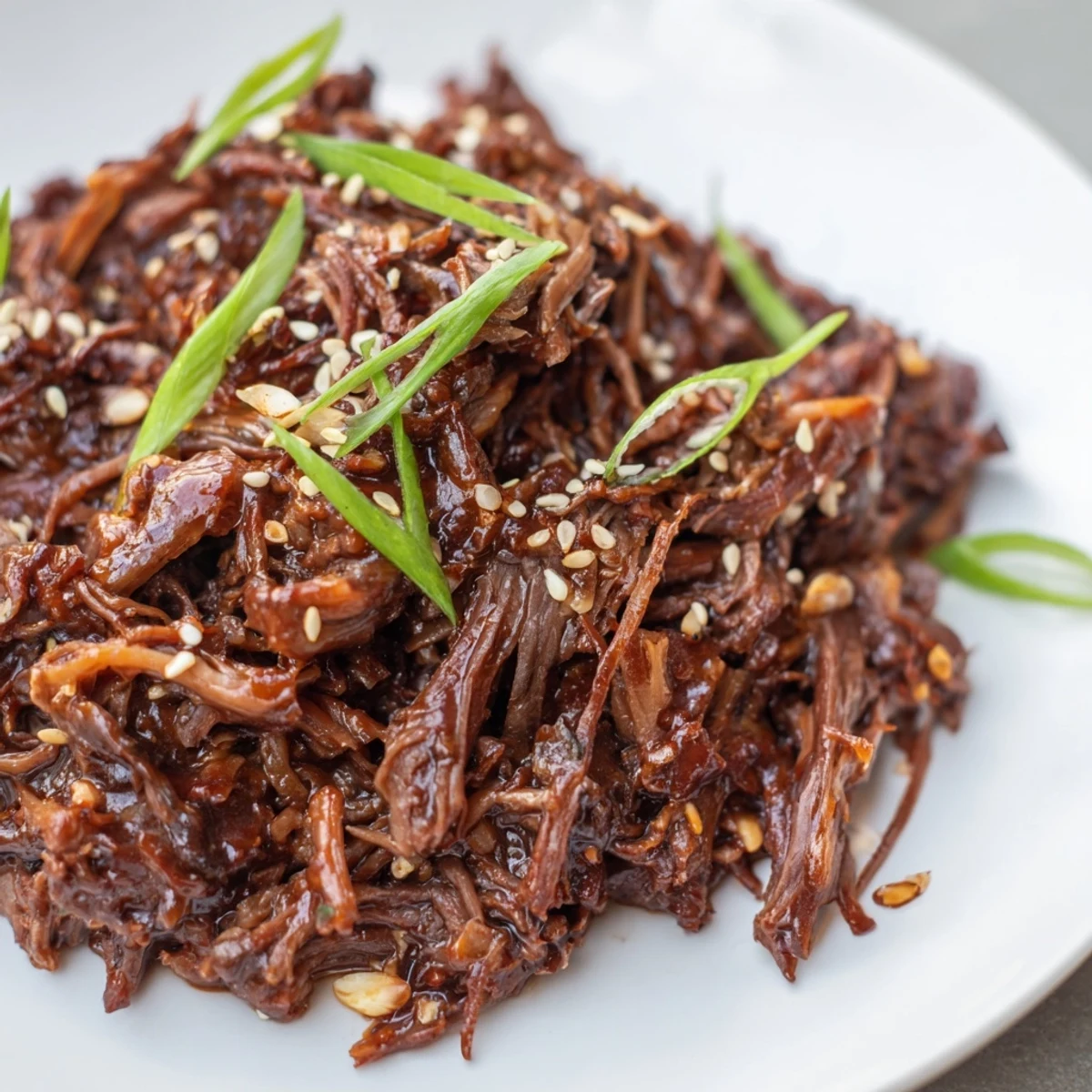 Fork-tender Slow Cooker Korean Beef piled on a plate with steamed vegetables, ready to serve as a hearty dairy-free dinner.