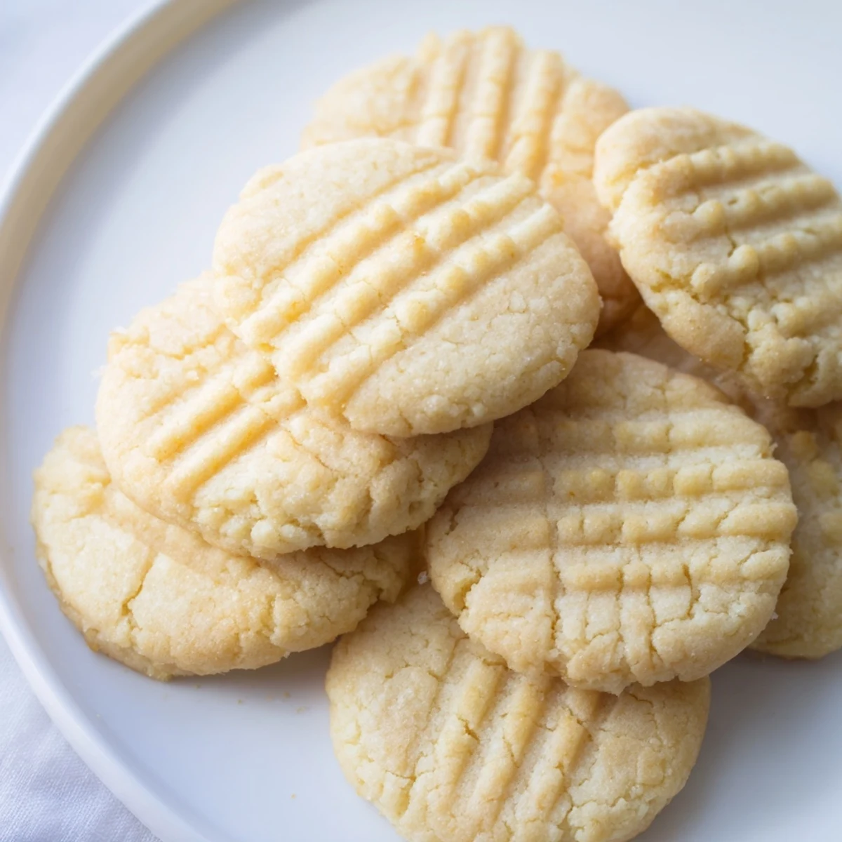 Close-up of freshly baked Keto Butter Cookies with crisscross fork marks on a cooling rack, showing their golden edges.