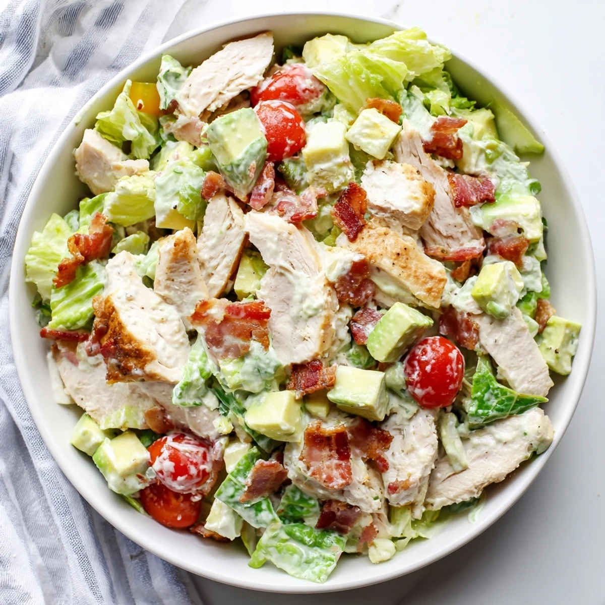 A plated serving of BLT Chicken Salad garnished with herbs and drizzled with homemade dressing.