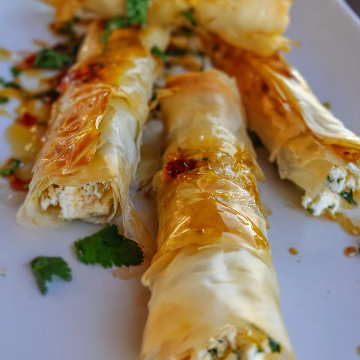 Oven Fried Feta Rolls With Chili Honey are arranged on a platter, ready to serve as a party appetizer.