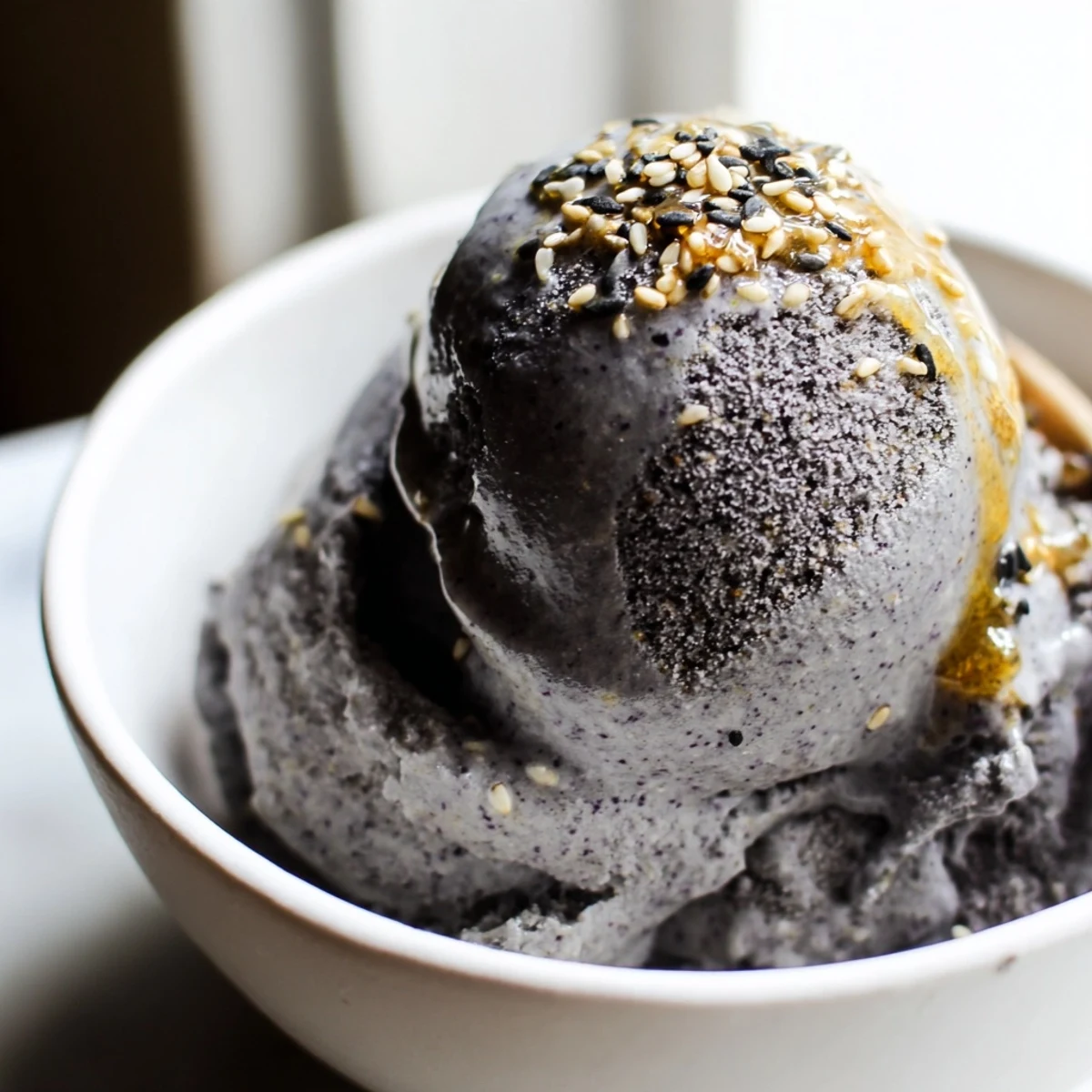 Freshly churned Toasted Black Sesame Ice Cream served in a waffle cone, showcasing its smooth, grayish texture.