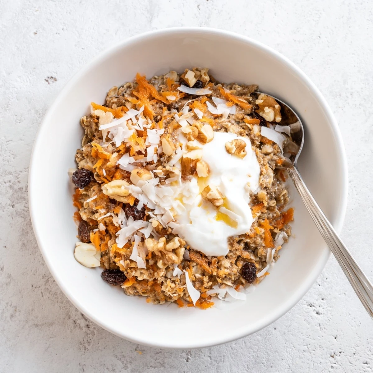 Creamy Carrot Cake Overnight Oats in a jar, layered with grated carrots, crunchy walnuts, and a drizzle of maple syrup.