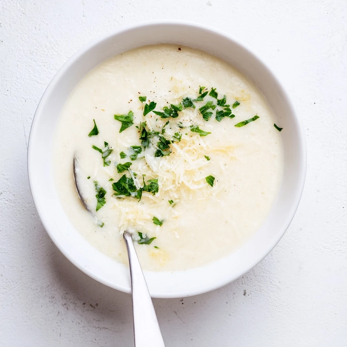 Steaming hot Asiago Roasted Garlic Cauliflower Soup topped with fresh chives and a side of crusty bread.