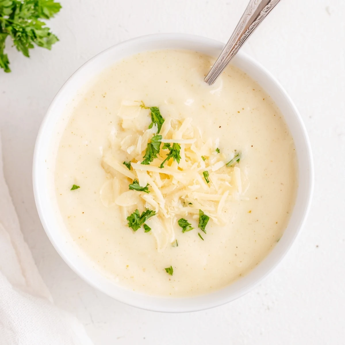 Golden roasted cauliflower and garlic swirl in this comforting Asiago Roasted Garlic Cauliflower Soup served in a rustic bowl.