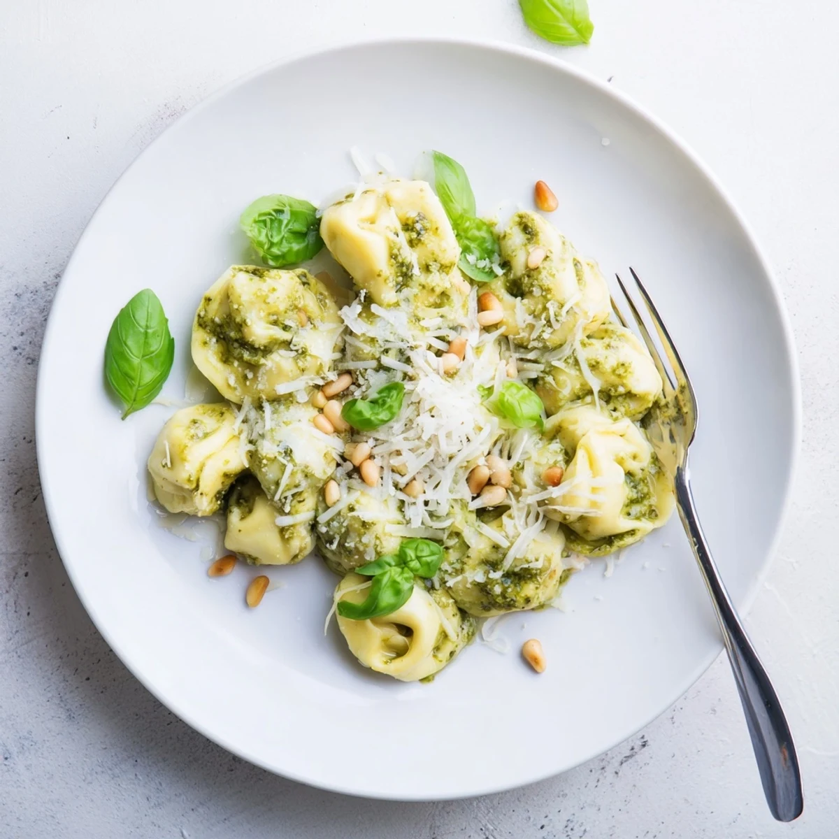 Steam rises from the skillet of Pesto Alfredo Tortellini, highlighting its vibrant green pesto and creamy sauce.