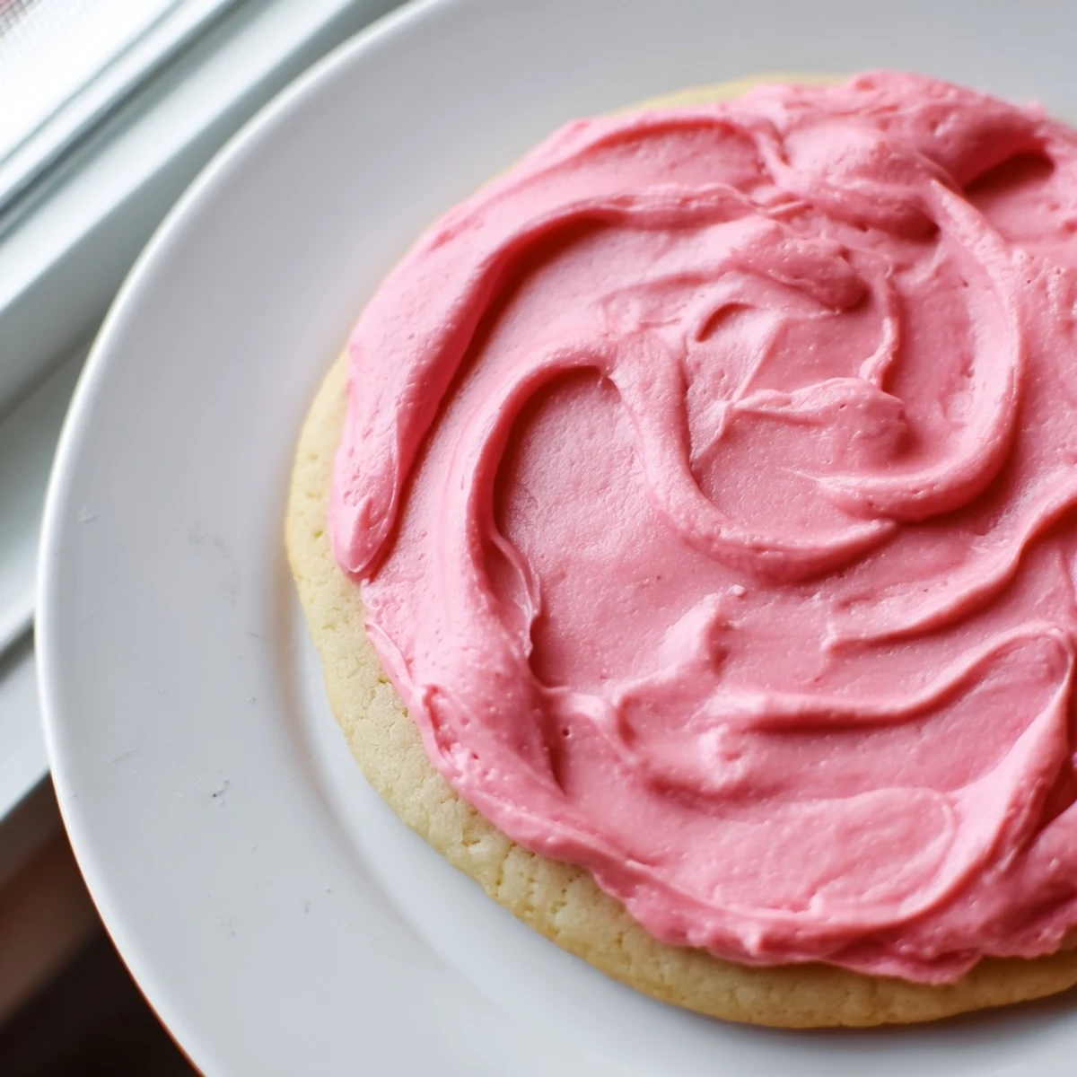 A close-up of Crumbl Pink Sugar Cookies with soft buttery texture and vibrant pink almond frosting.