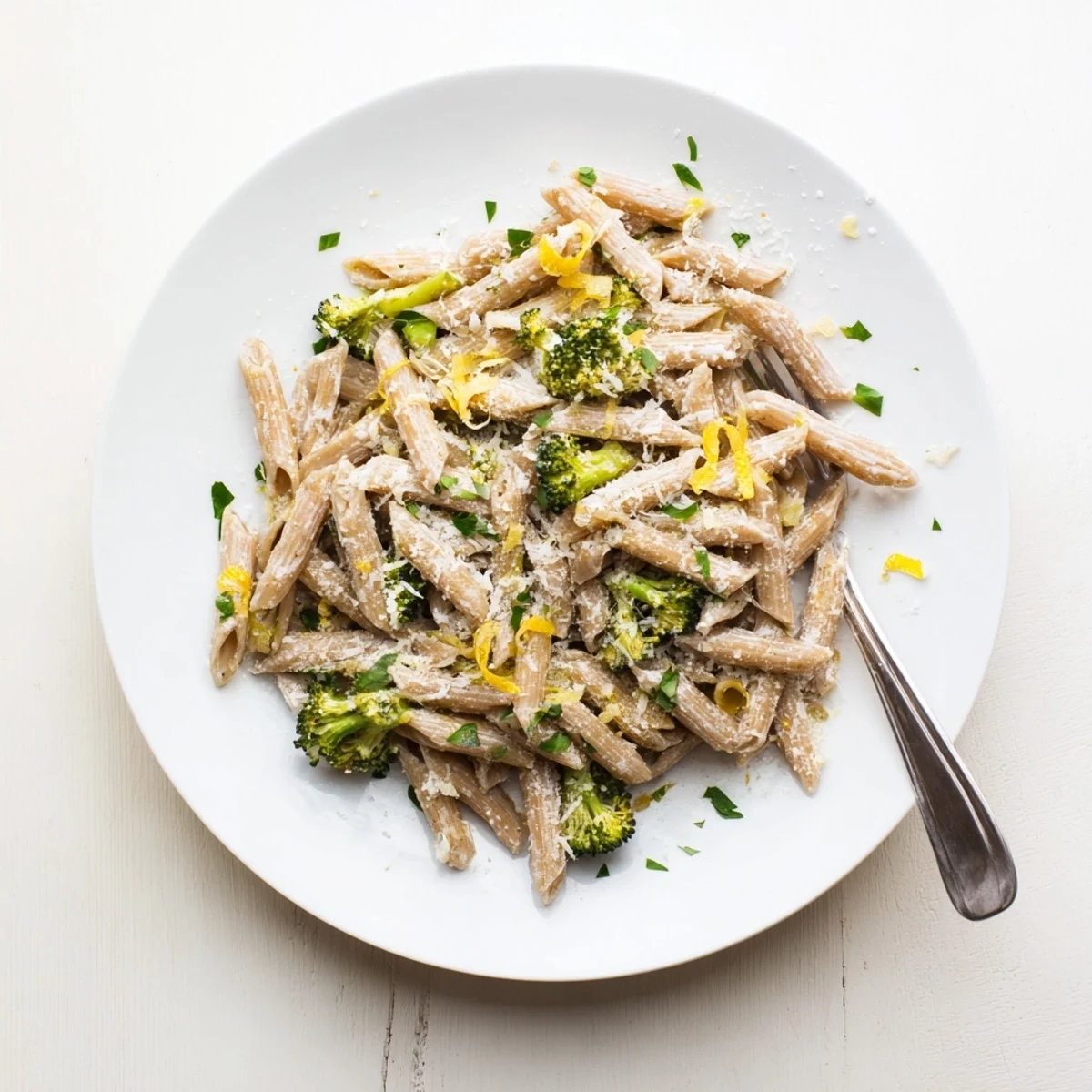 A close-up of Easy Healthy Broccoli Pasta in a white bowl, garnished with fresh parsley and a wedge of lemon for a bright finish.
