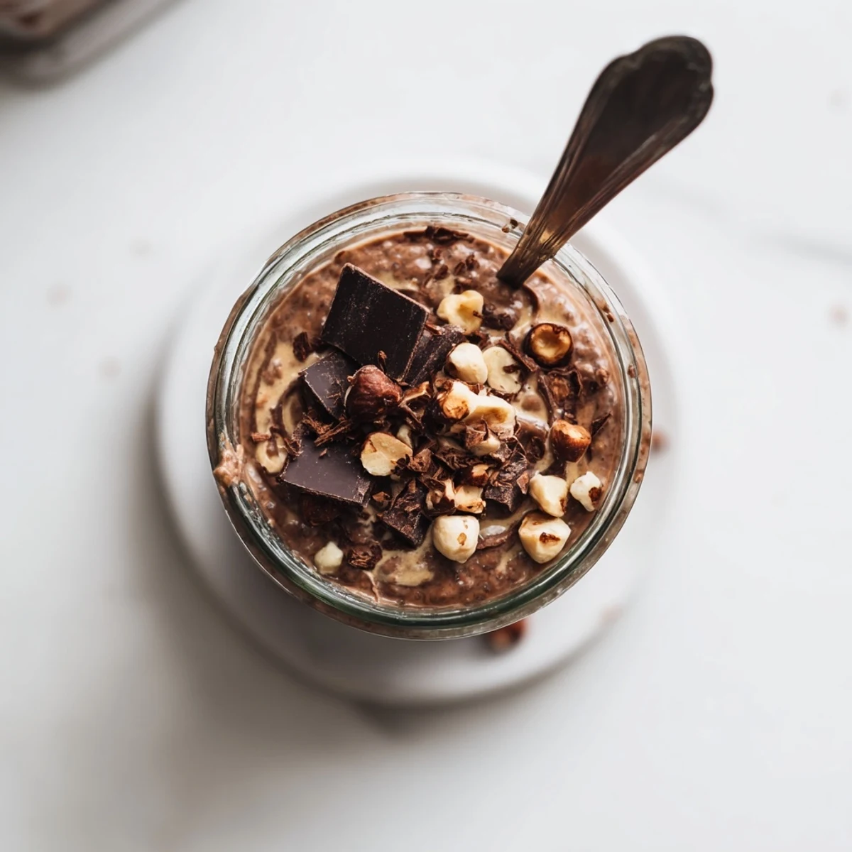 Ferrero Rocher Protein Overnight Oats topped with dark chocolate pieces and halved Ferrero Rocher