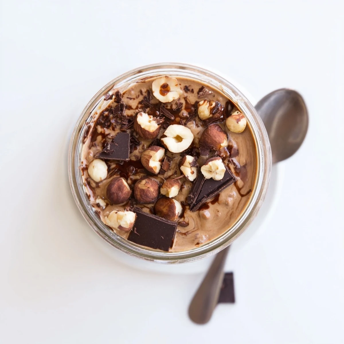Two jars of Ferrero Rocher Protein Overnight Oats with chocolate drizzle and chopped hazelnuts