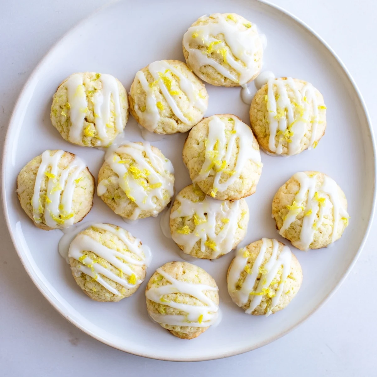 Fresh Limoncello Cookies arranged on a white plate, their buttery texture and bright yellow glaze perfect for a sunny spring gathering.