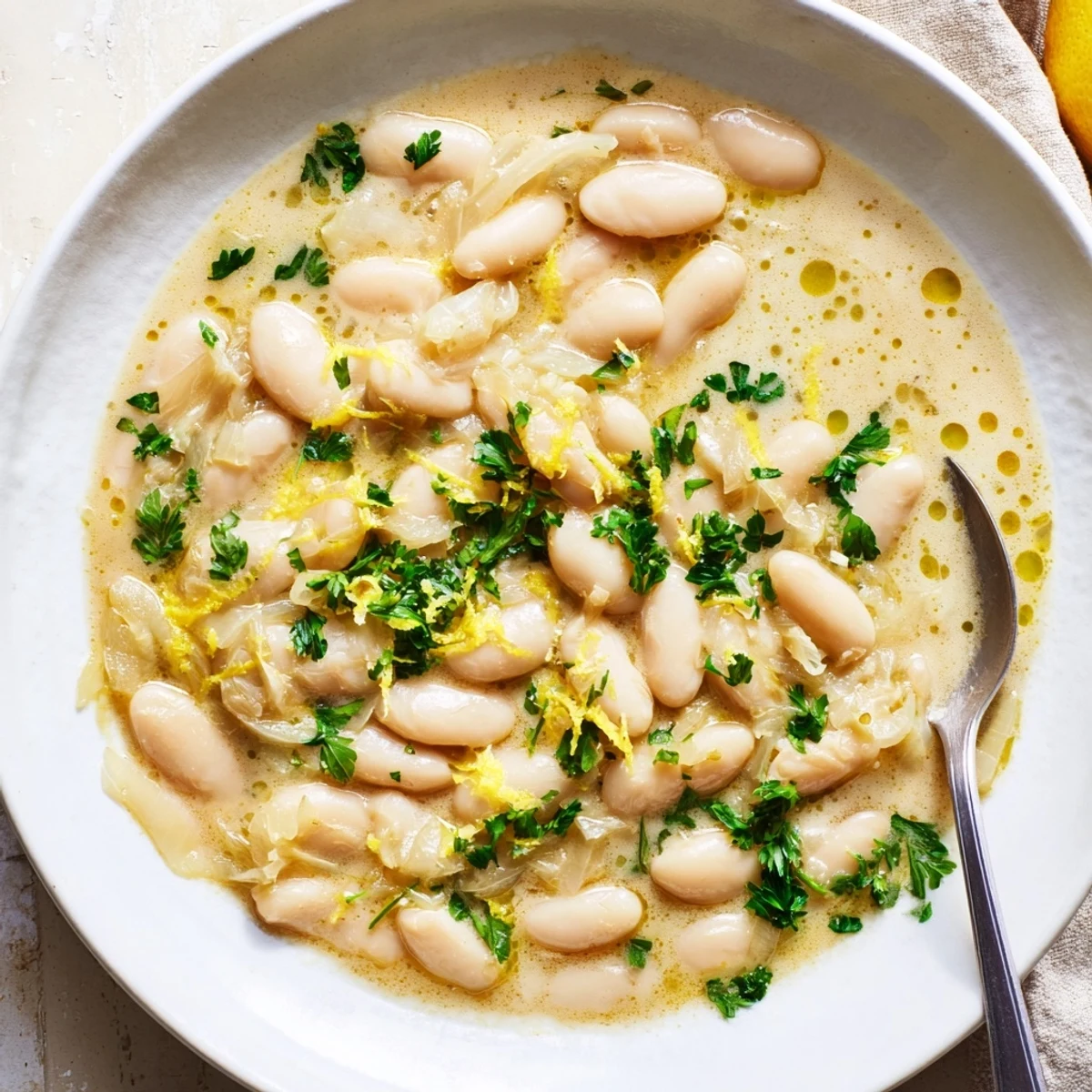 Golden bowl of miso butter brothy beans garnished with parsley and served with crusty bread