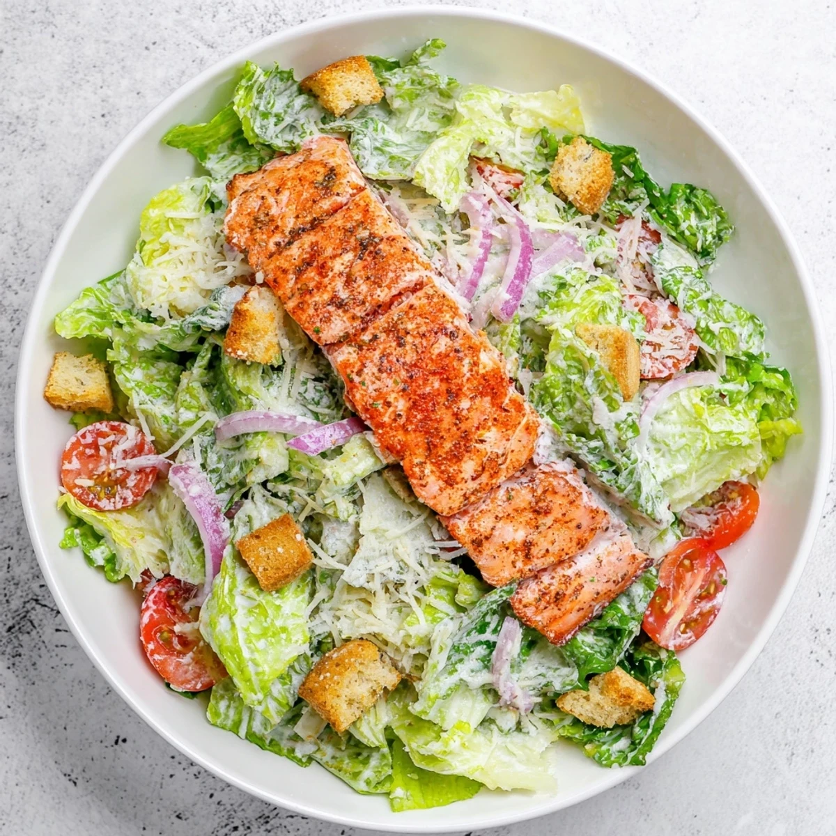 Grilled salmon Caesar salad with crisp romaine, croutons, and creamy homemade dressing served on white plate