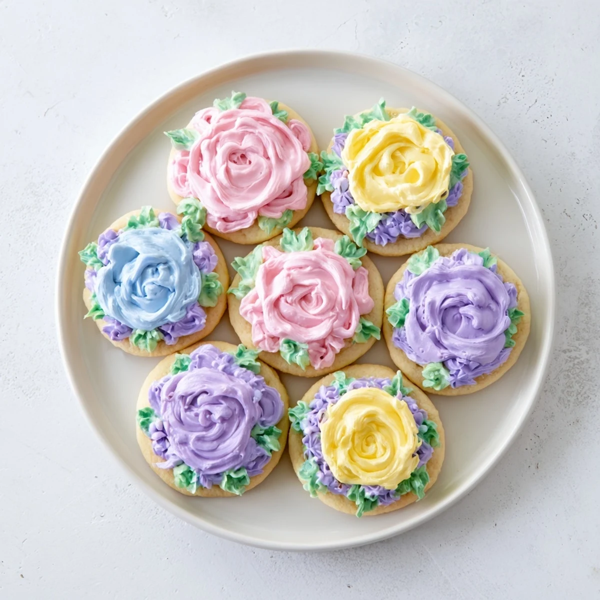 Golden sugar cookies adorned with vibrant piped buttercream flowers in pink and yellow