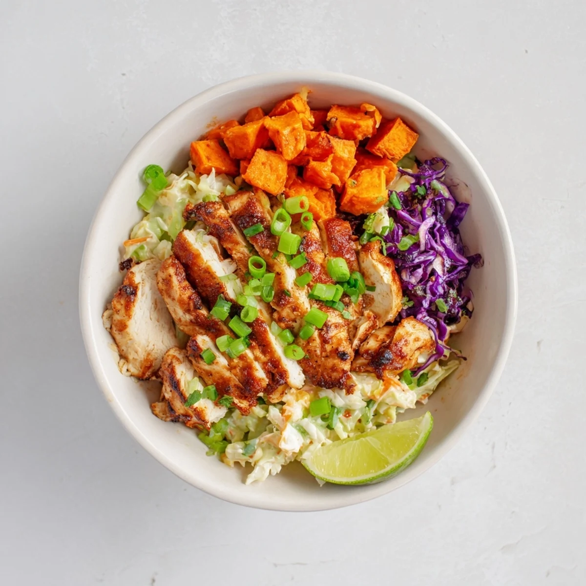 Hearty BBQ chicken bowl featuring tender meat sweet potatoes and crunchy cabbage slaw