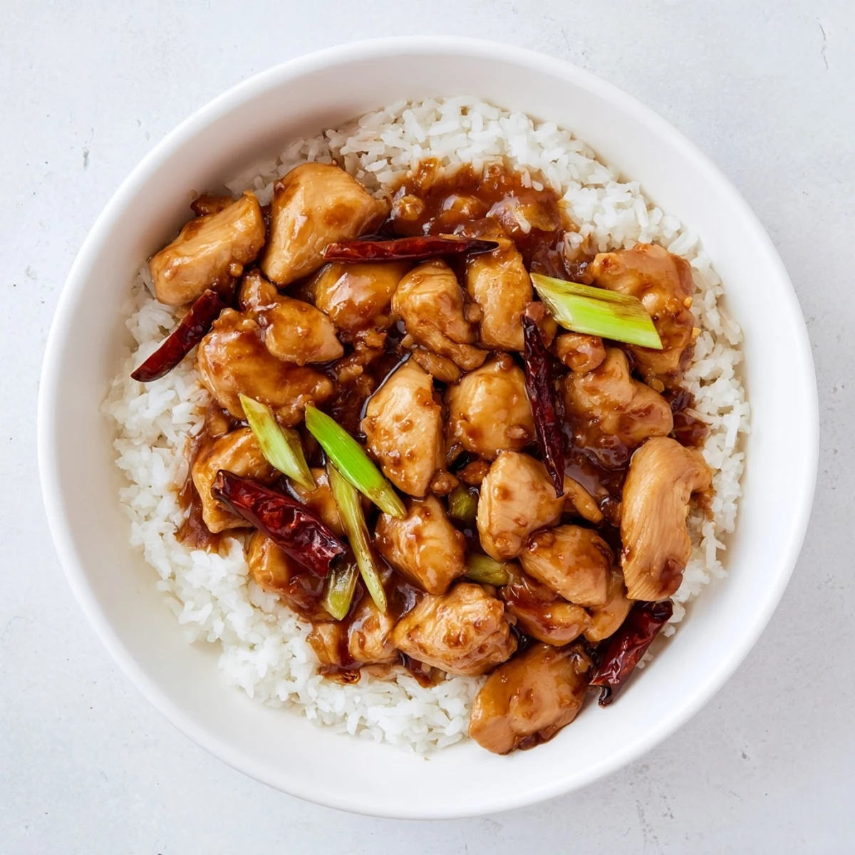 Tender stir-fried Mongolian chicken simmered in savory sweet sauce served on fluffy steamed rice with sesame garnish