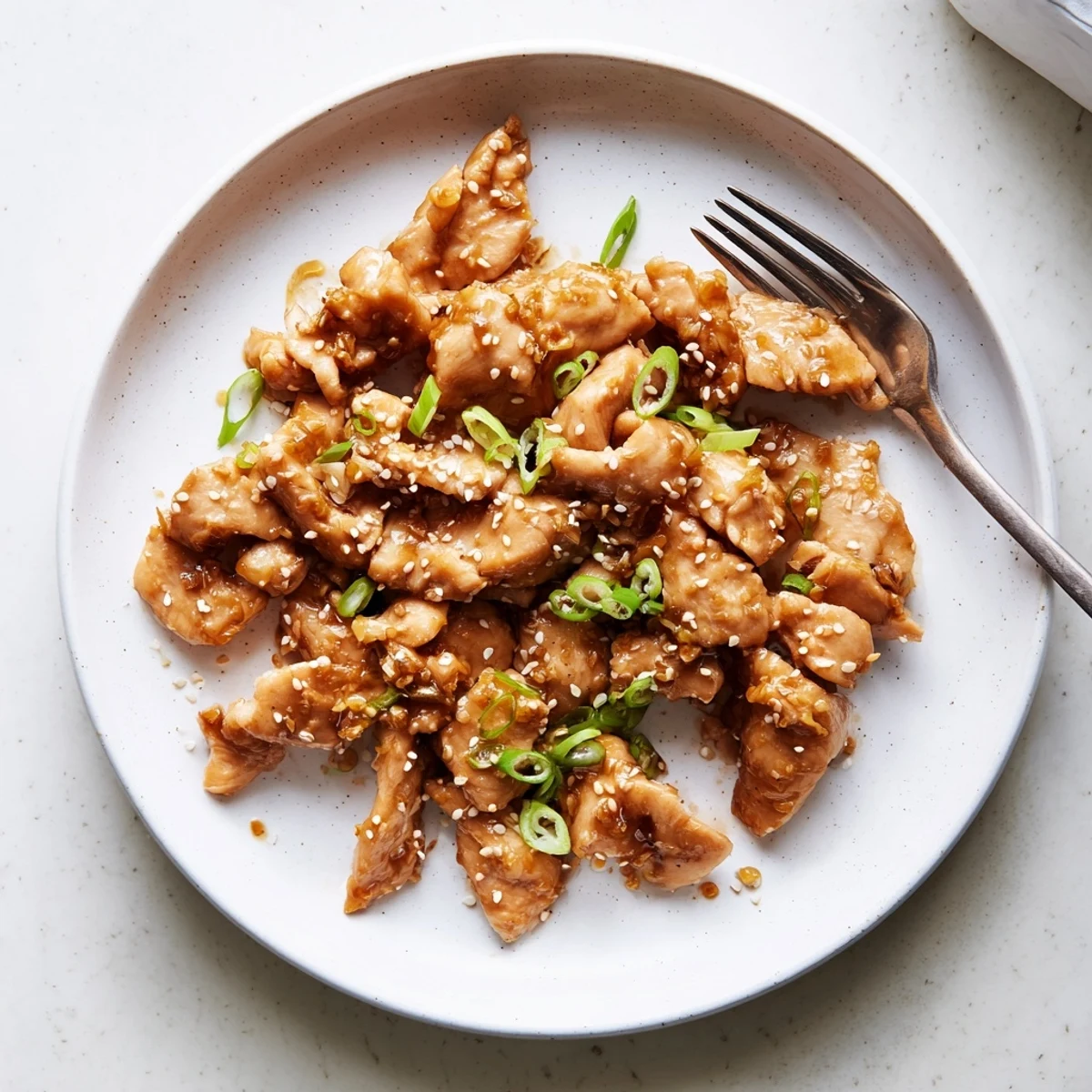 Easy Crock Pot Sesame Chicken garnished with green onions over white rice