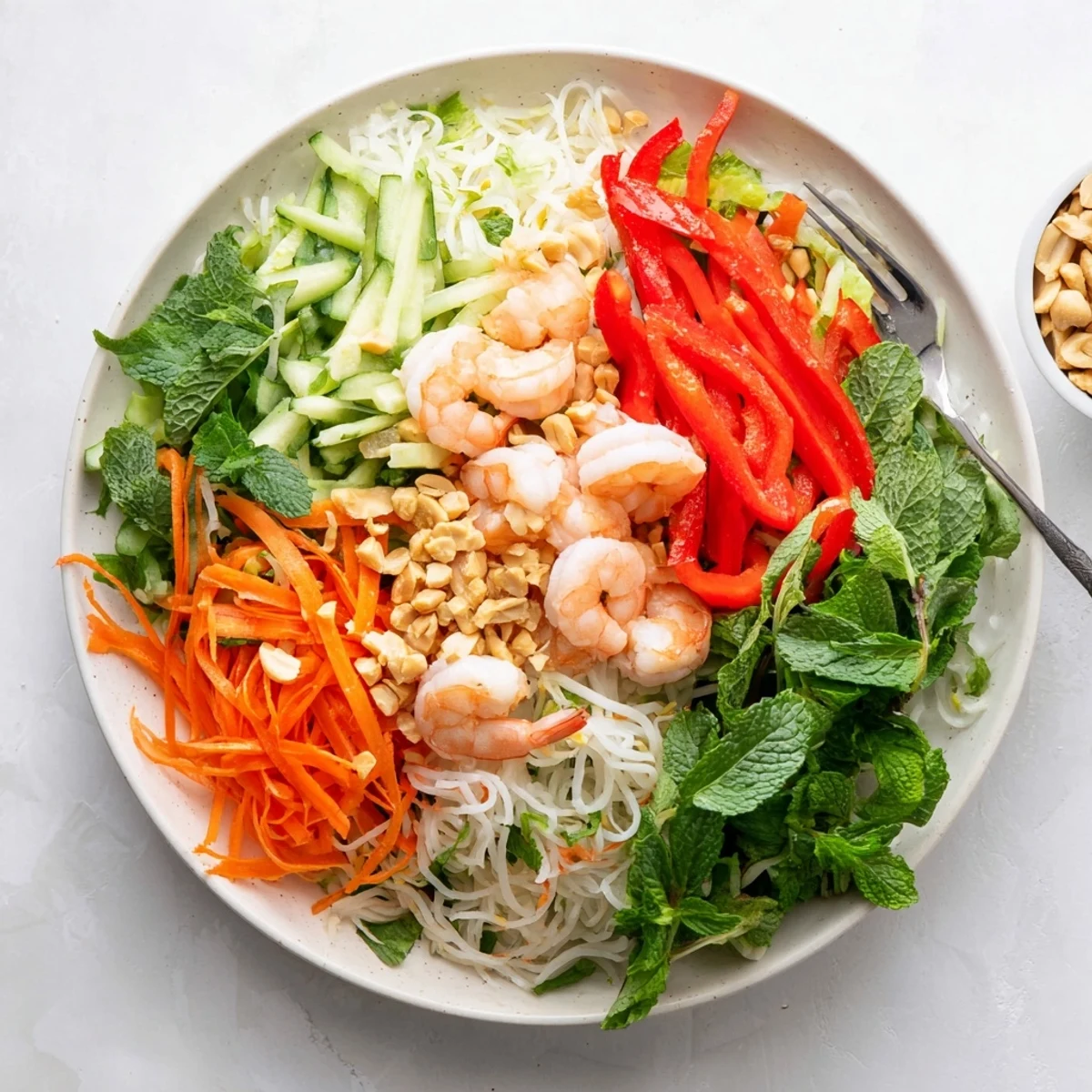 Fresh spring roll salad with spicy ginger dressing featuring crisp vegetables, tender shrimp, and fragrant herbs in a vibrant bowl