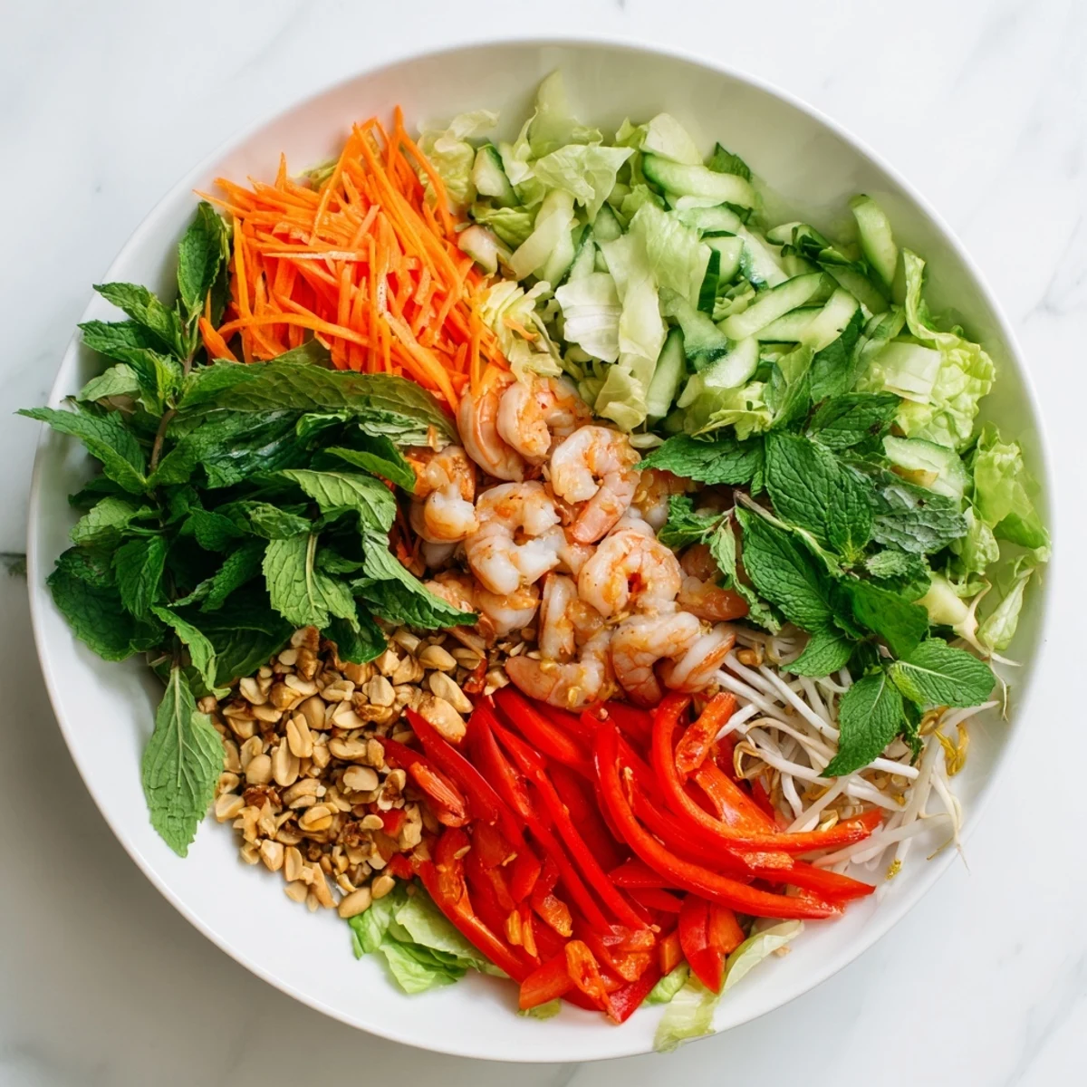 Colorful spring roll salad tossed in zesty ginger dressing with julienned cucumber, carrots, mint, cilantro, and plump cooked shrimp
