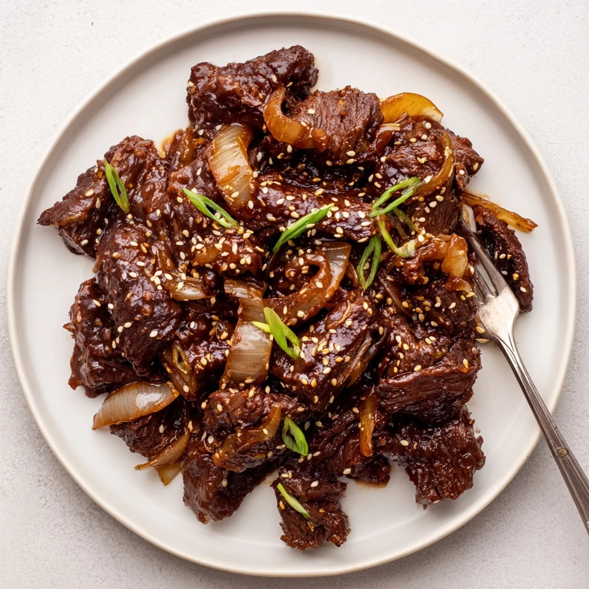 Savory slow cooker Korean beef with caramelized edges garnished with fresh green onions and sesame seeds