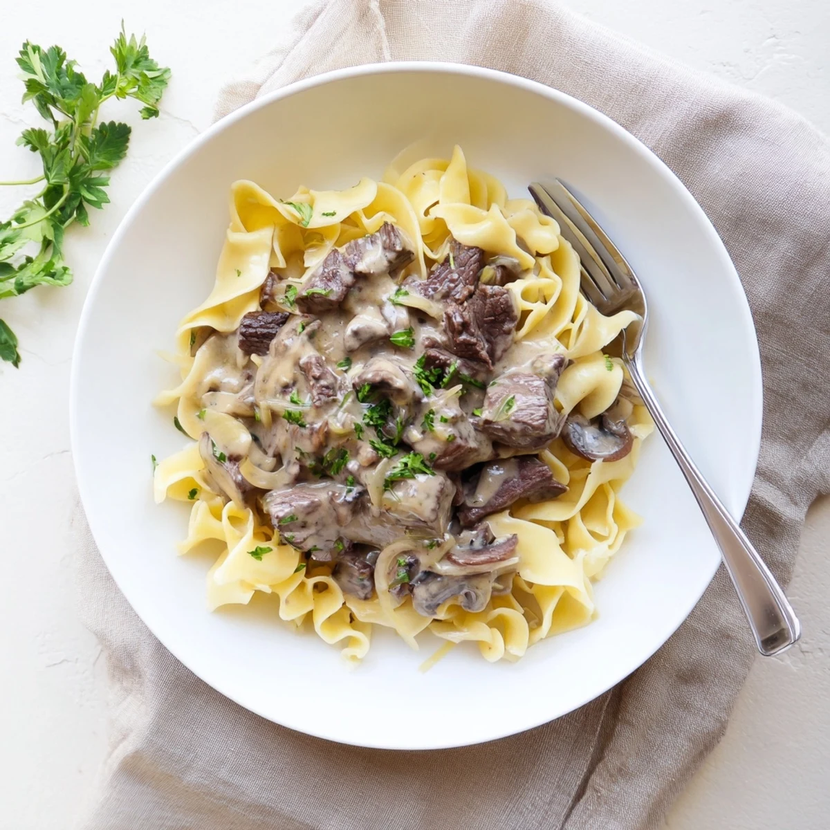 Golden beef stroganoff with tender meat strips and creamy mushroom sauce over noodles
