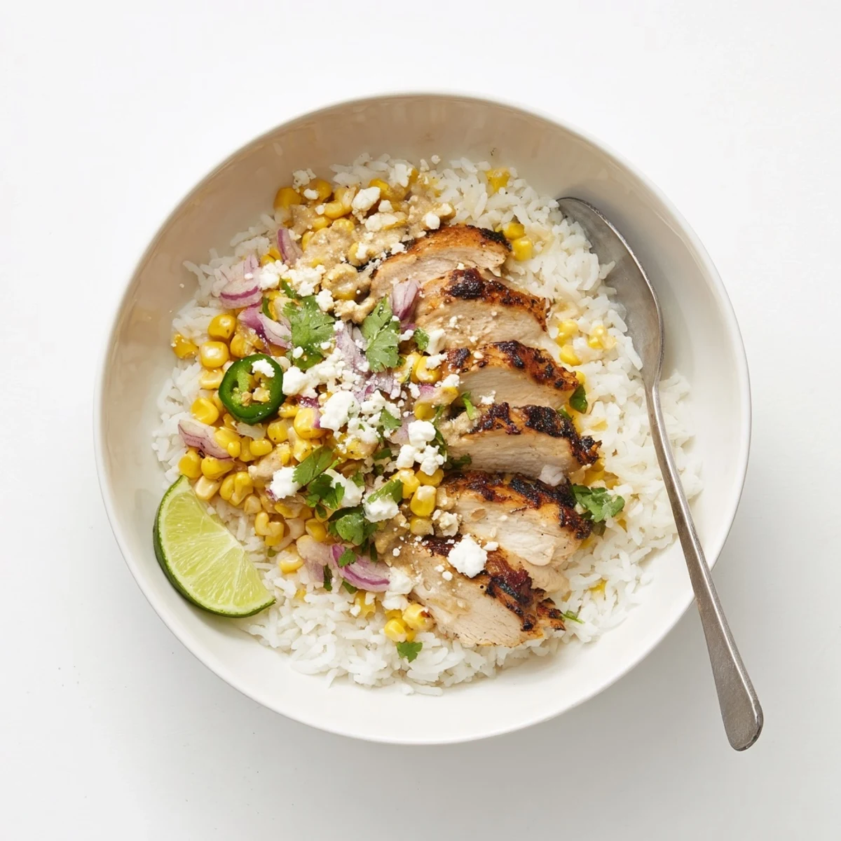 Easy street corn chicken bowl featuring charred corn kernels, creamy cotija sauce, and seasoned grilled chicken