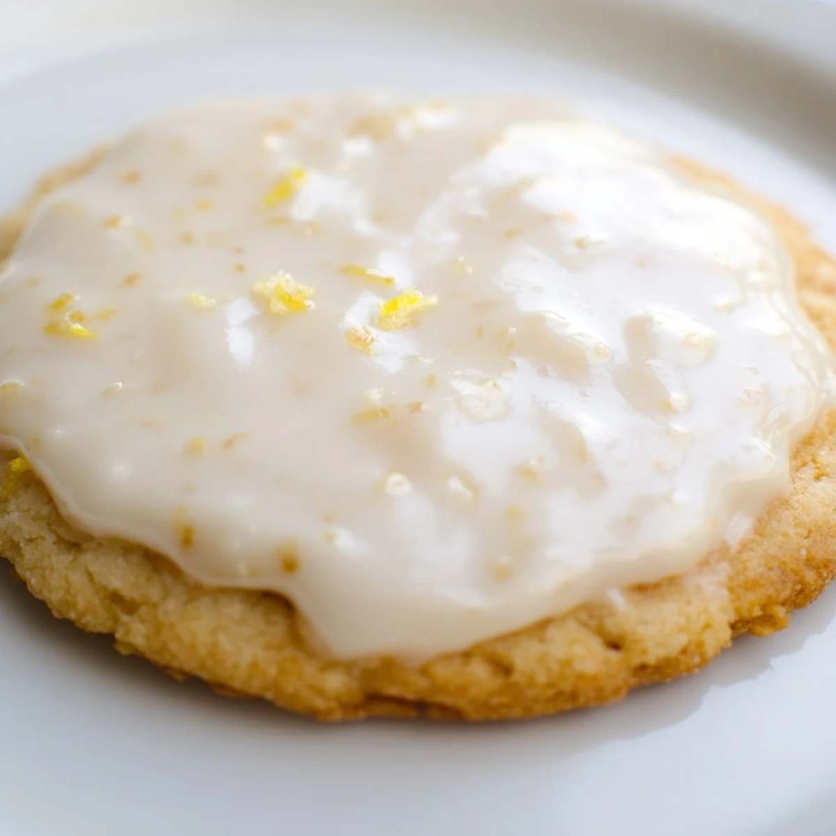 Soft buttery lemon cookies topped with zesty frosting arranged on a white serving platter