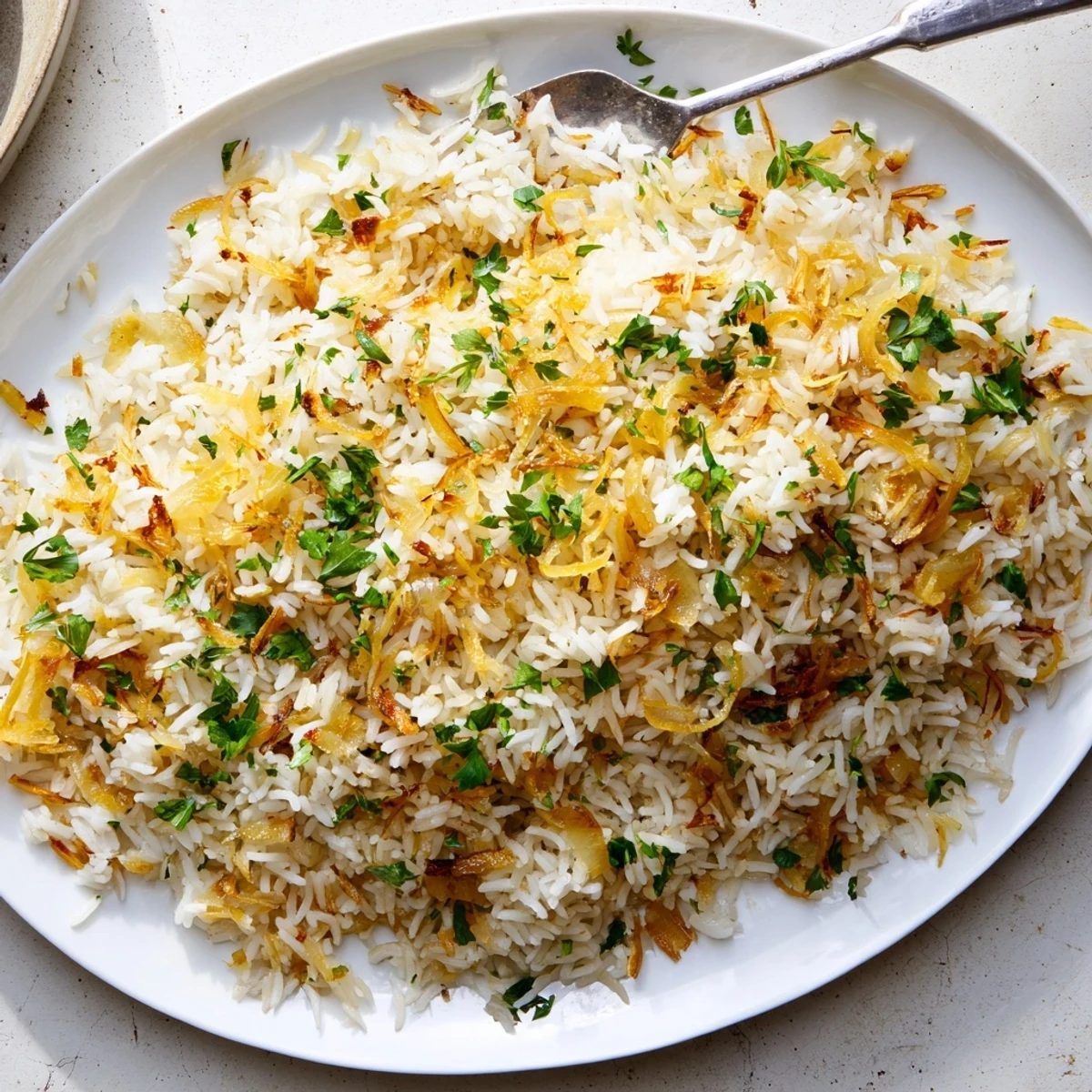 Creamy French onion butter rice served in a bowl alongside caramelized onion strands