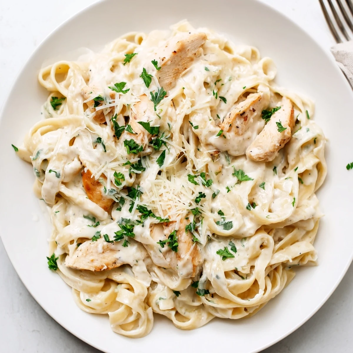 Steaming bowl of garlic parmesan chicken pasta with tender breast pieces and white creamy sauce