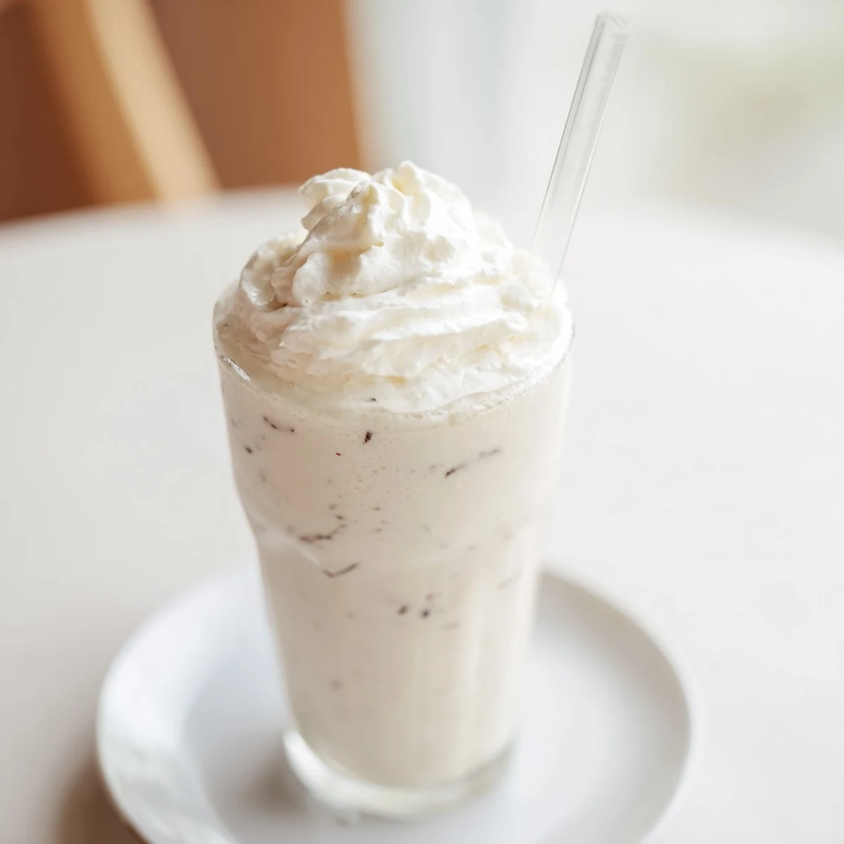 Creamy vanilla bean frappuccino topped with fluffy whipped cream in a chilled glass