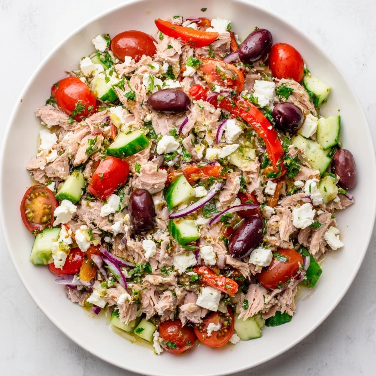 Spoon lifting vibrant tuna salad with cherry tomatoes, cucumber, and red peppers from serving bowl