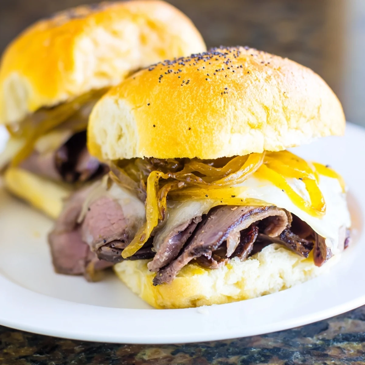 Golden French dip sliders stacked with roast beef and melted provolone cheese on sweet Hawaiian rolls