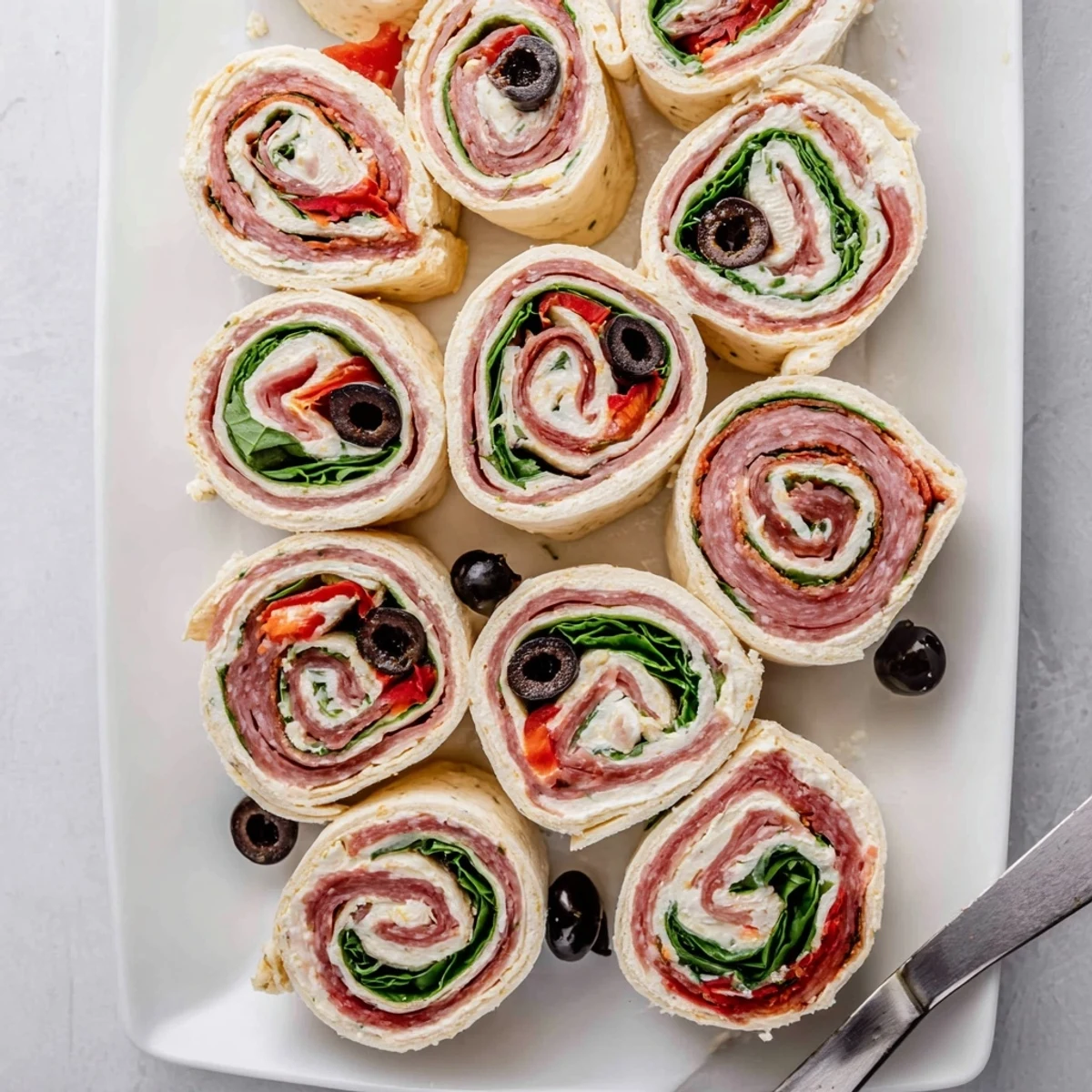 Close up of Italian pinwheel sandwiches showing cross section of cream cheese spread, ham, pepperoni, and melted provolone