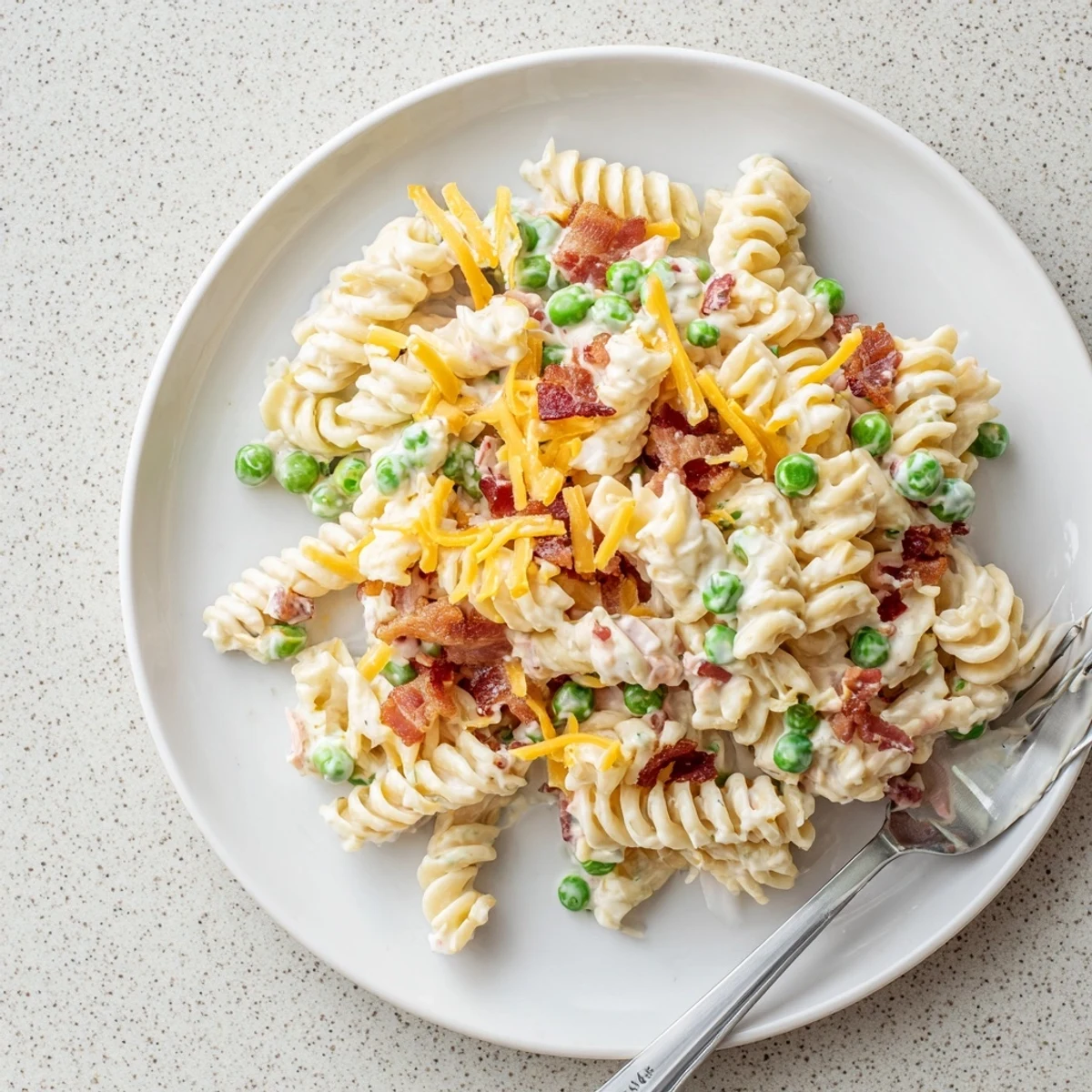 American side dish featuring cheesy pasta salad with sour cream, peas and bacon crumbles