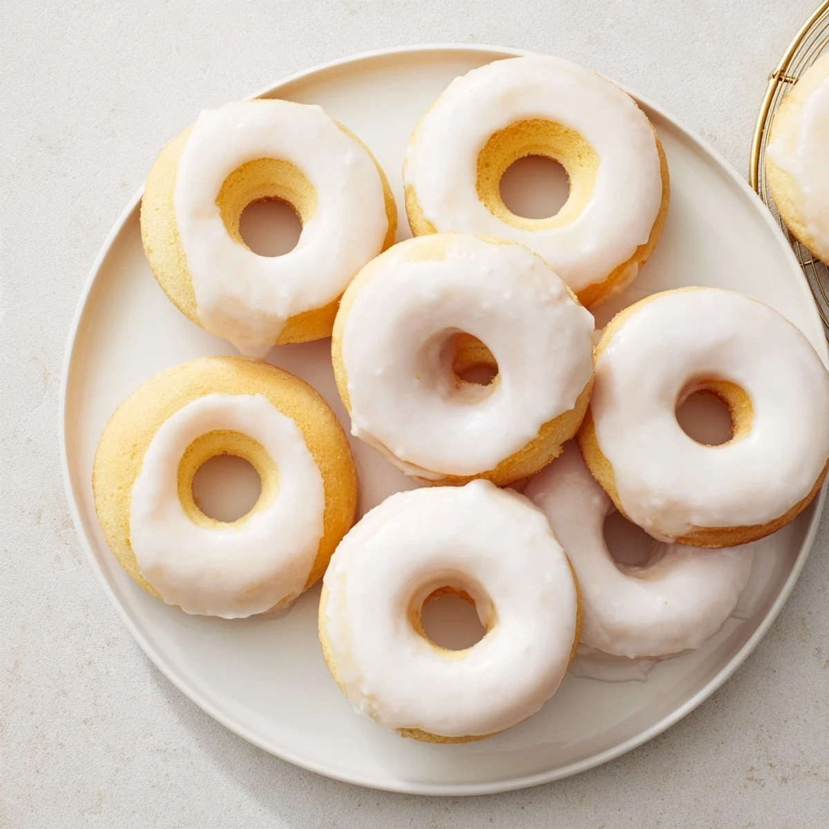 Golden baked Greek yogurt cake donuts topped with sweet vanilla glaze and colorful sprinkles on a wire rack