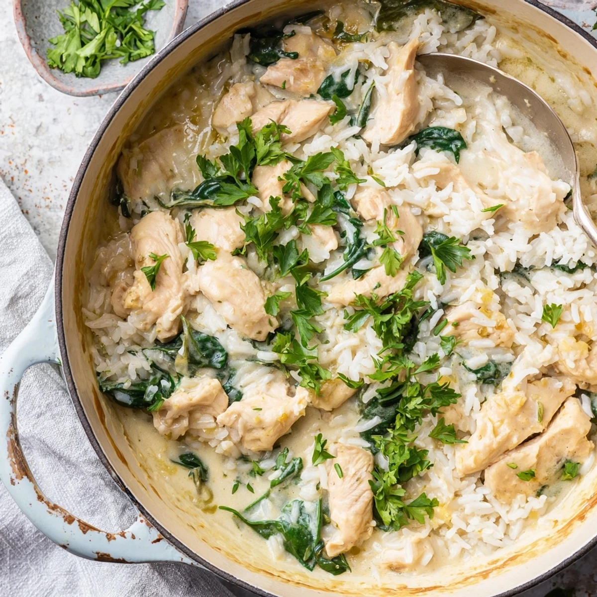 Golden chicken breasts resting on creamy rice with melted cheese sauce in a Dutch oven
