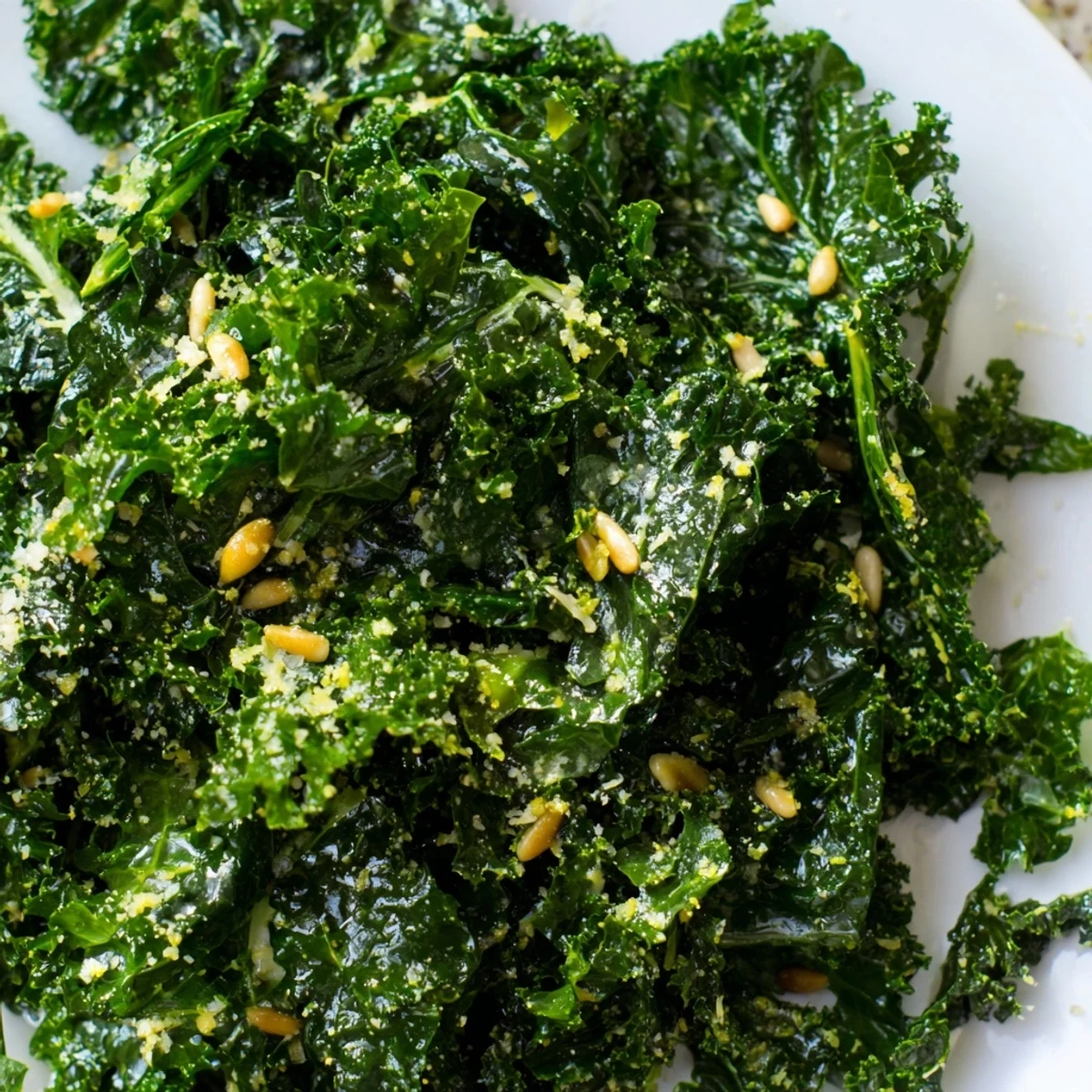 Garlic Lemon Parmesan Kale Salad in a rustic wooden bowl with shaved cheese and toasted pine nuts