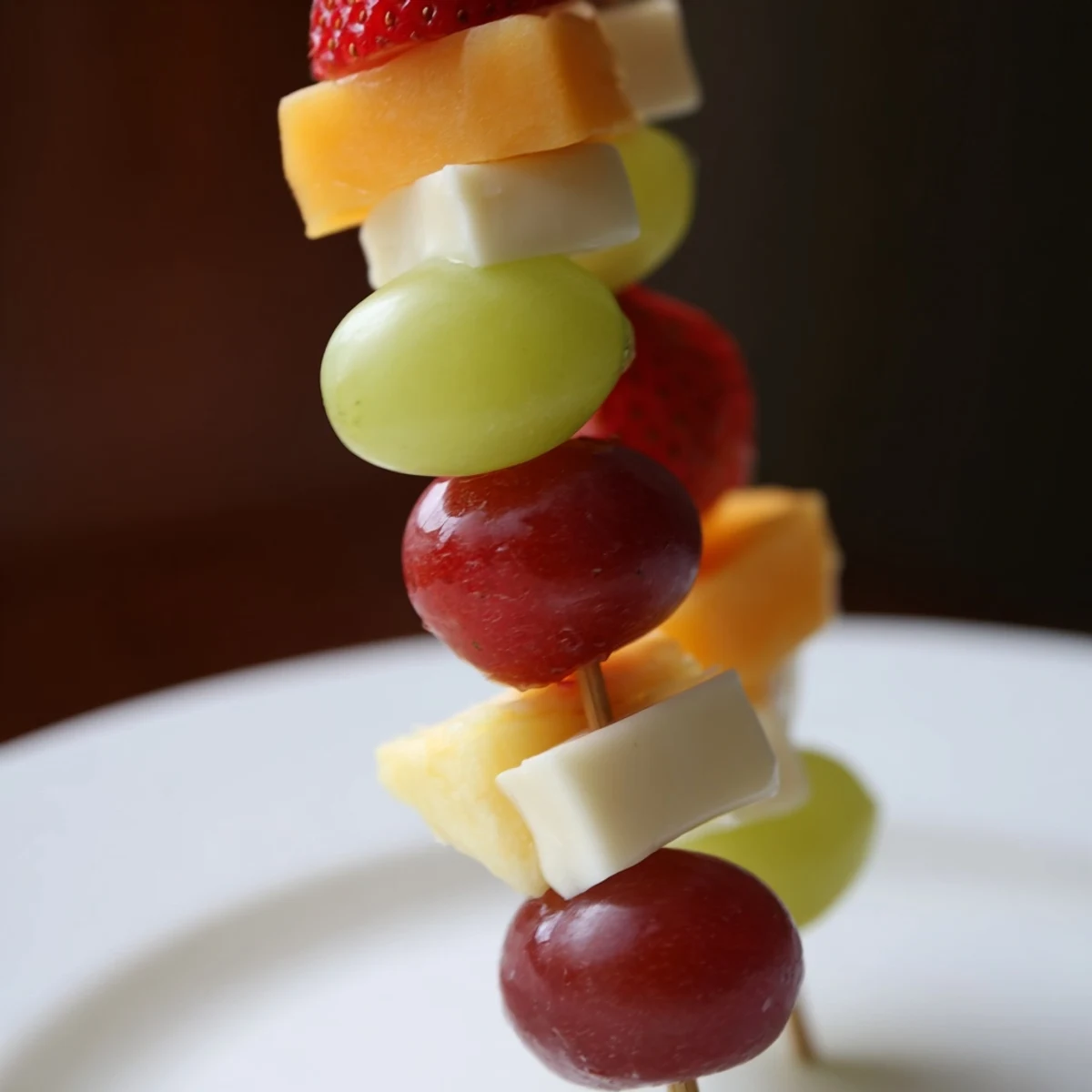 Colorful fruit and cheese kabobs arranged on platter with fresh mint garnish