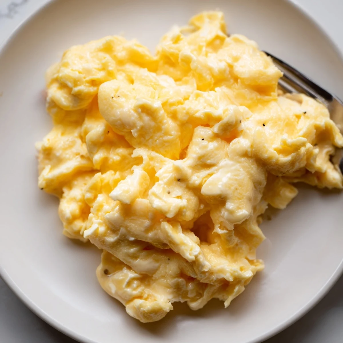 Soft yellow scrambled eggs in a bowl garnished with snipped chives