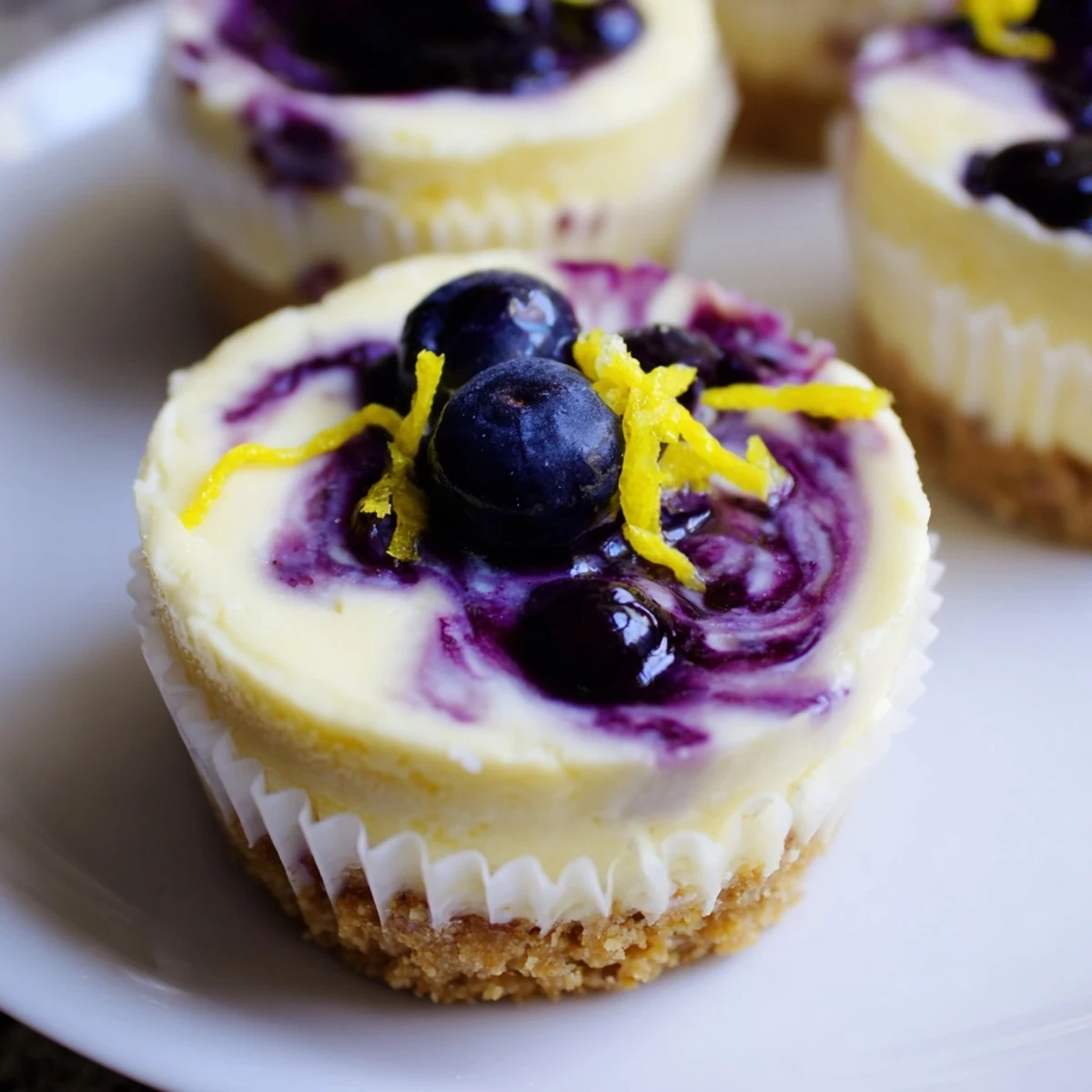 Bite-sized mini lemon blueberry cheesecakes garnished with fresh berries and bright lemon zest