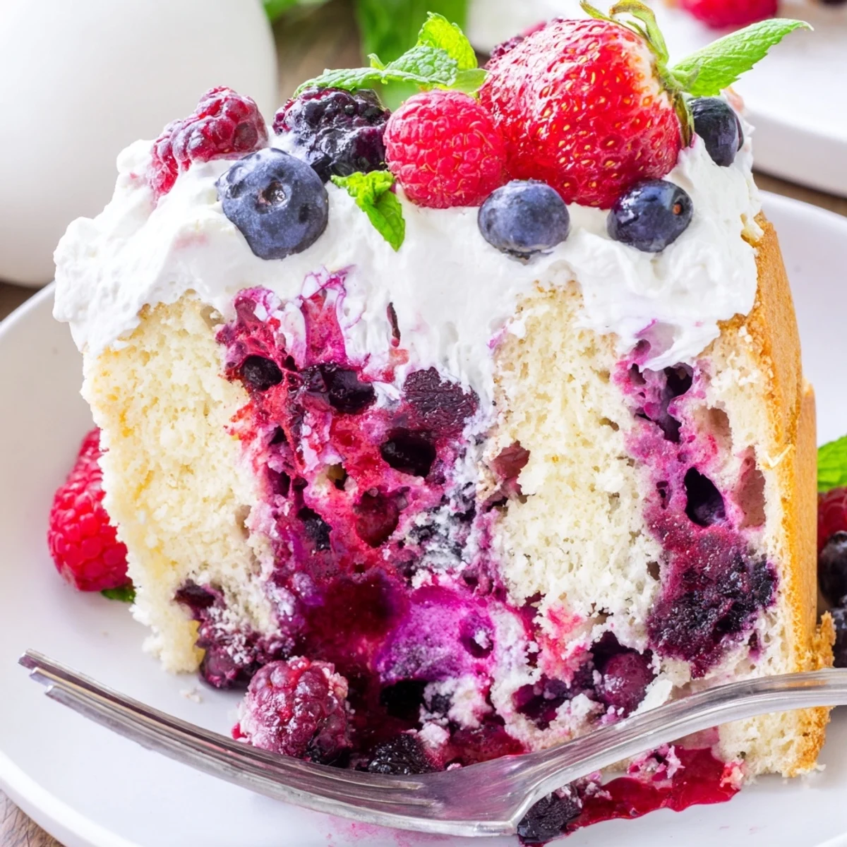 Moist Summer Berry Poke Cake with jewel-toned berry sauce soaking into tender vanilla crumb.
